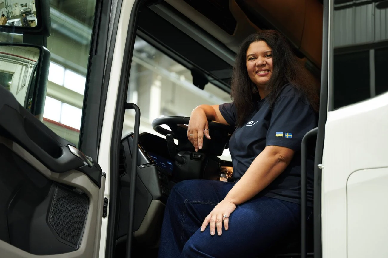 En kvinna som sitter i en lastbil och ler mot kameran.