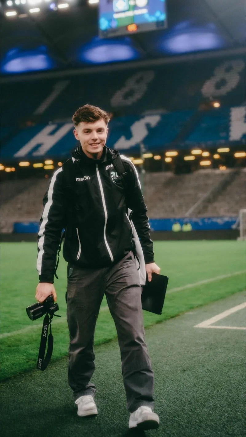Elias Reimpell im Volksparkstadion in Hamburg mit Kamera, Rucksack und Fotografie-Equipment.