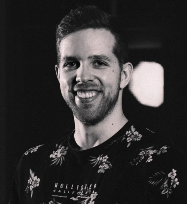 Schwarz-weiß Foto eines lächelnden Mannes im Blumenmuster T-Shirt.
