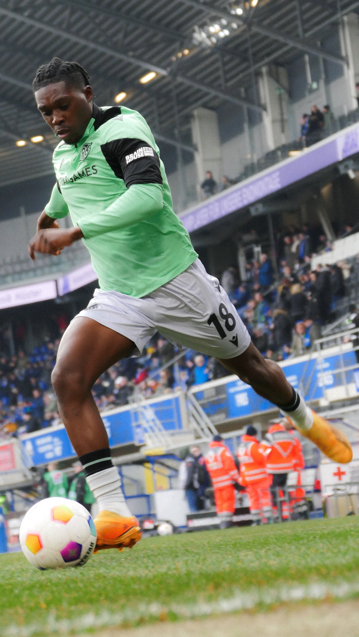 Fußballspieler in grünem Trikot beim Dribbling auf dem Spielfeld.
