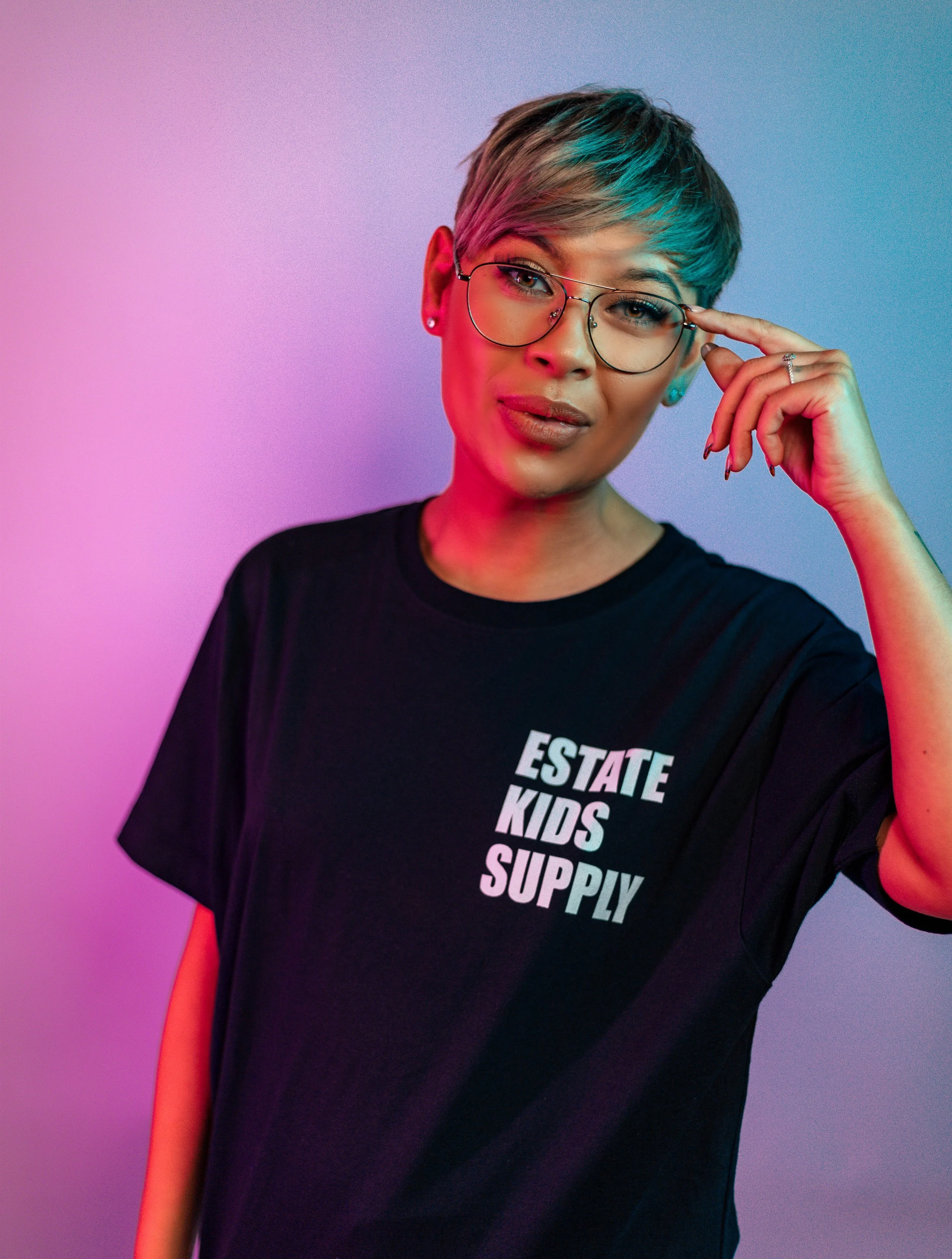 A model in a black thsirt and glasses with blue and pink lighting either side