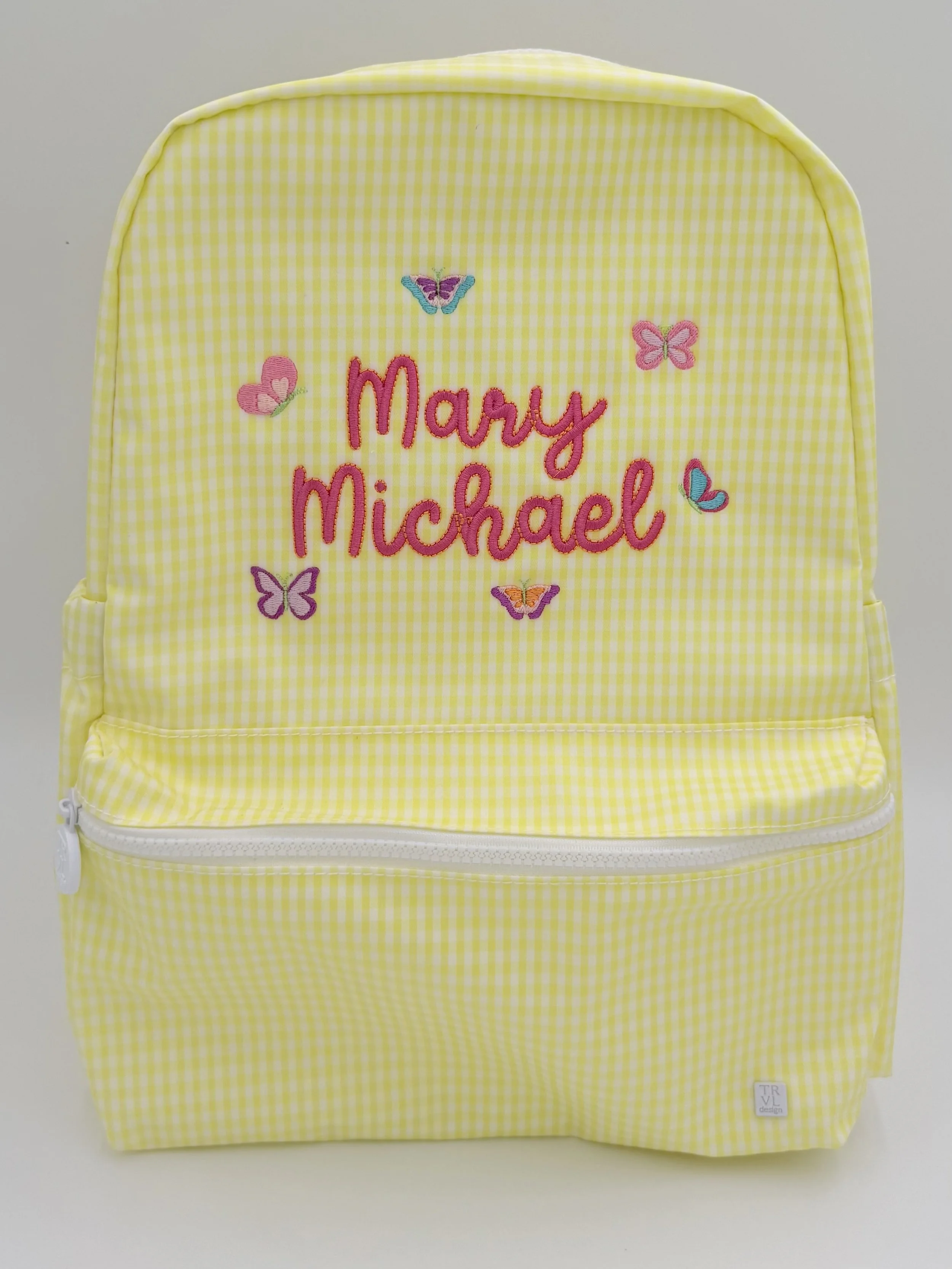 Yellow gingham backpack with embroidered pink, purple, blue, and orange butterflies and the name "Mary Michael" in pink embroidery.
