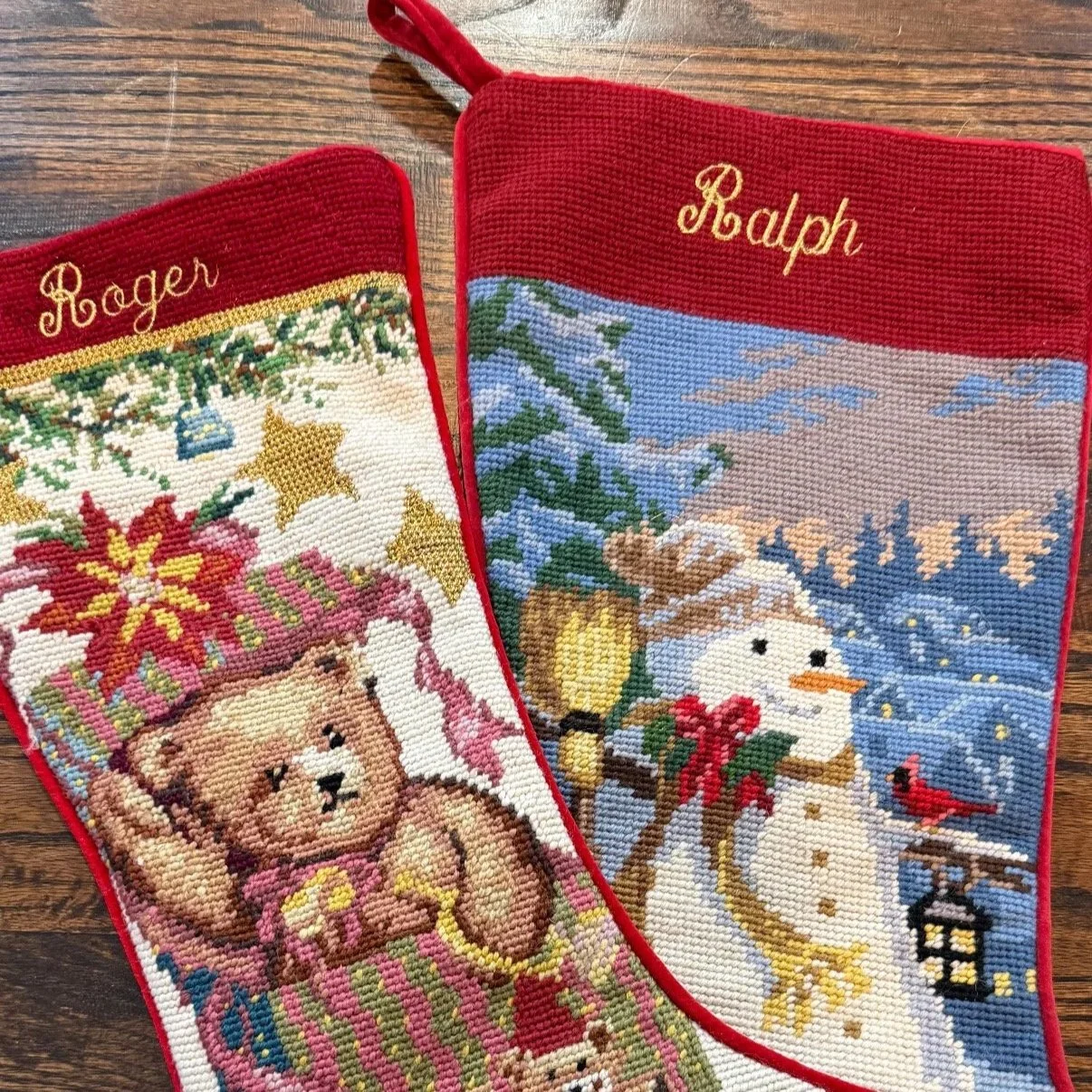 Christmas stockings with embroidered scenes of teddy bears, a snowman, and holiday decorations, personalized with the names Roger and Ralph.