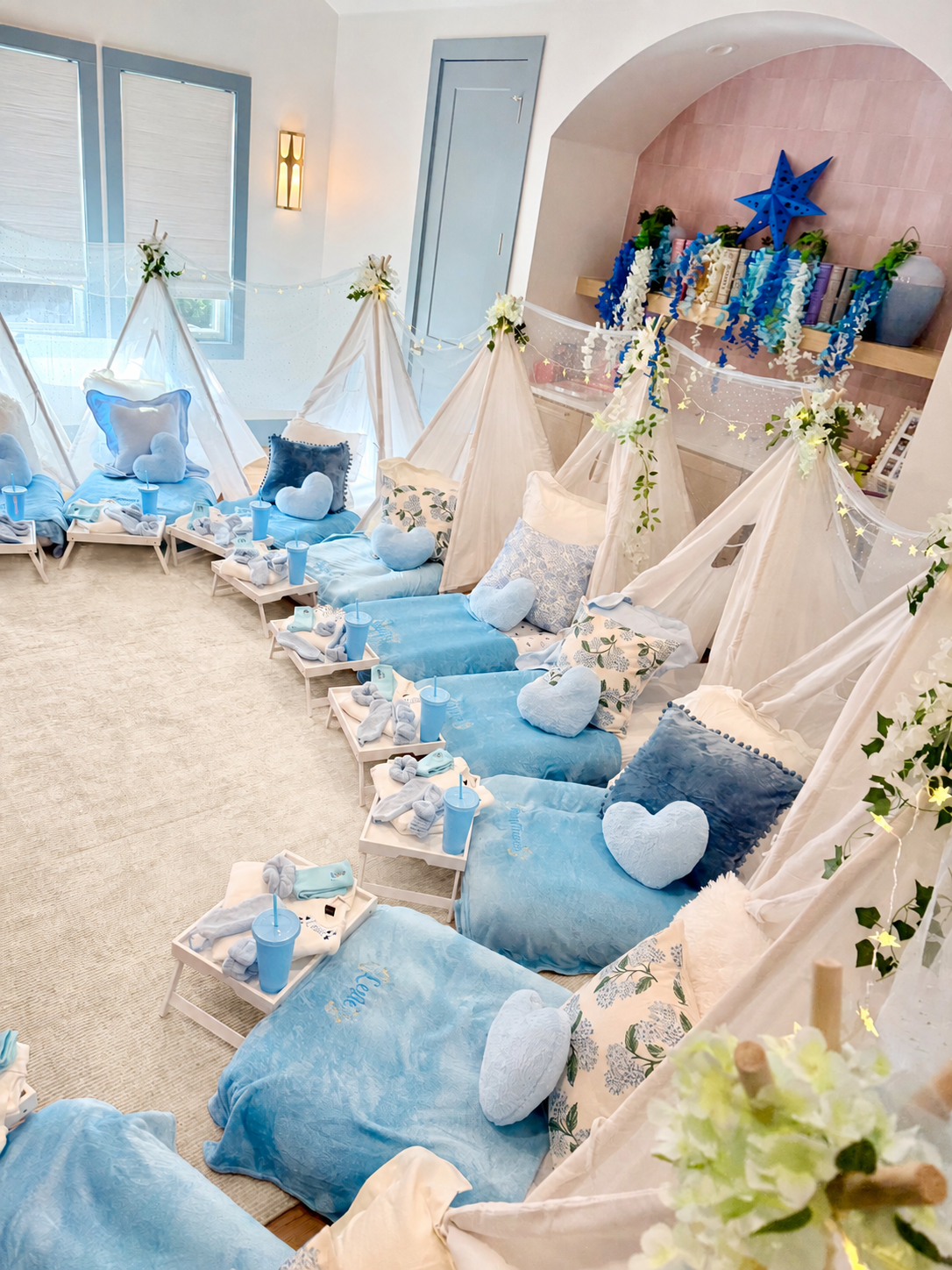 Blue-themed sleepover party with small tents, floor mattresses, cushions, personalized blankets, and individual snack trays.
