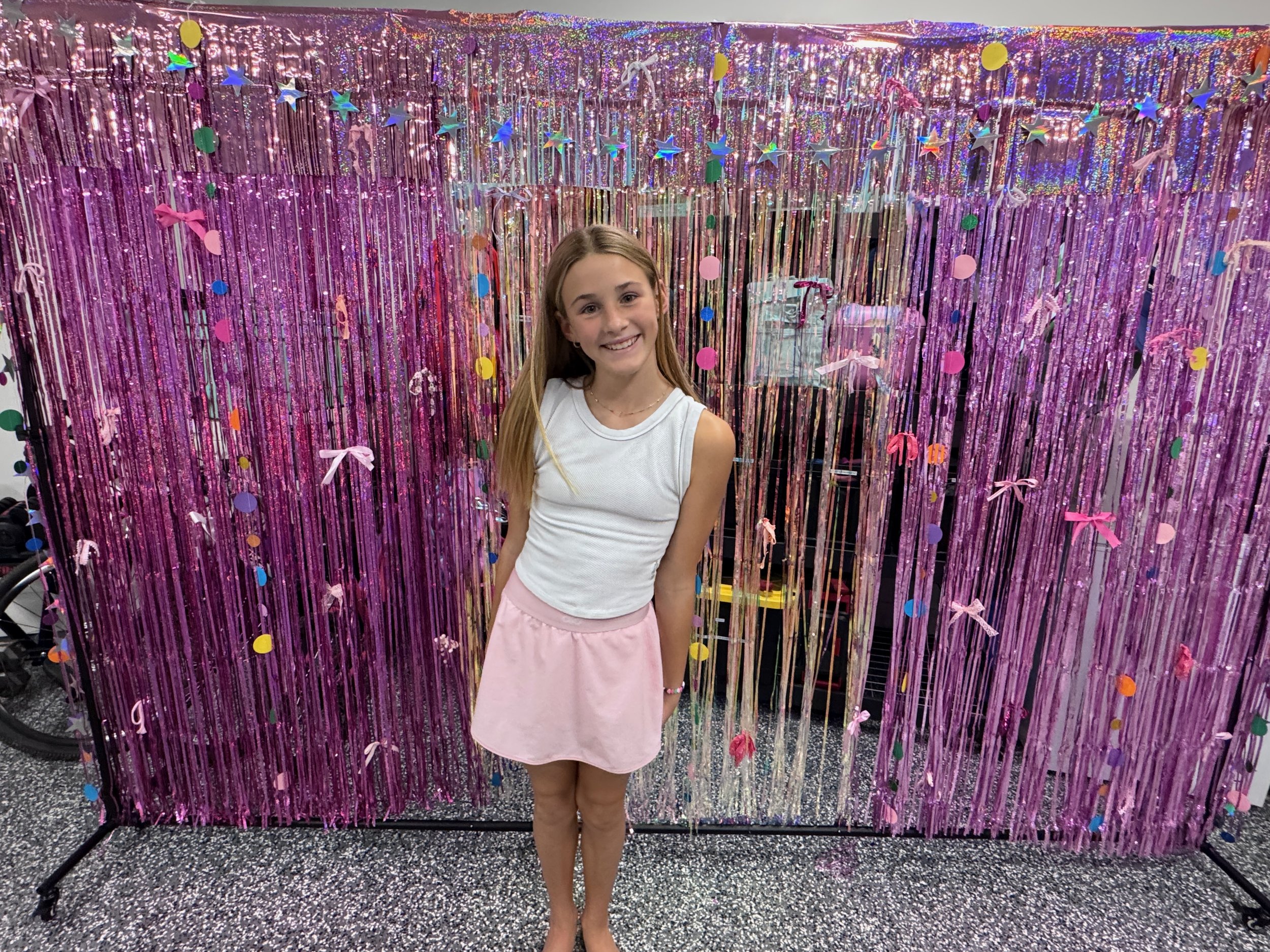 A party guest in front of the pink tinsel backdrop at Blakely’s live embroidery celebration.
