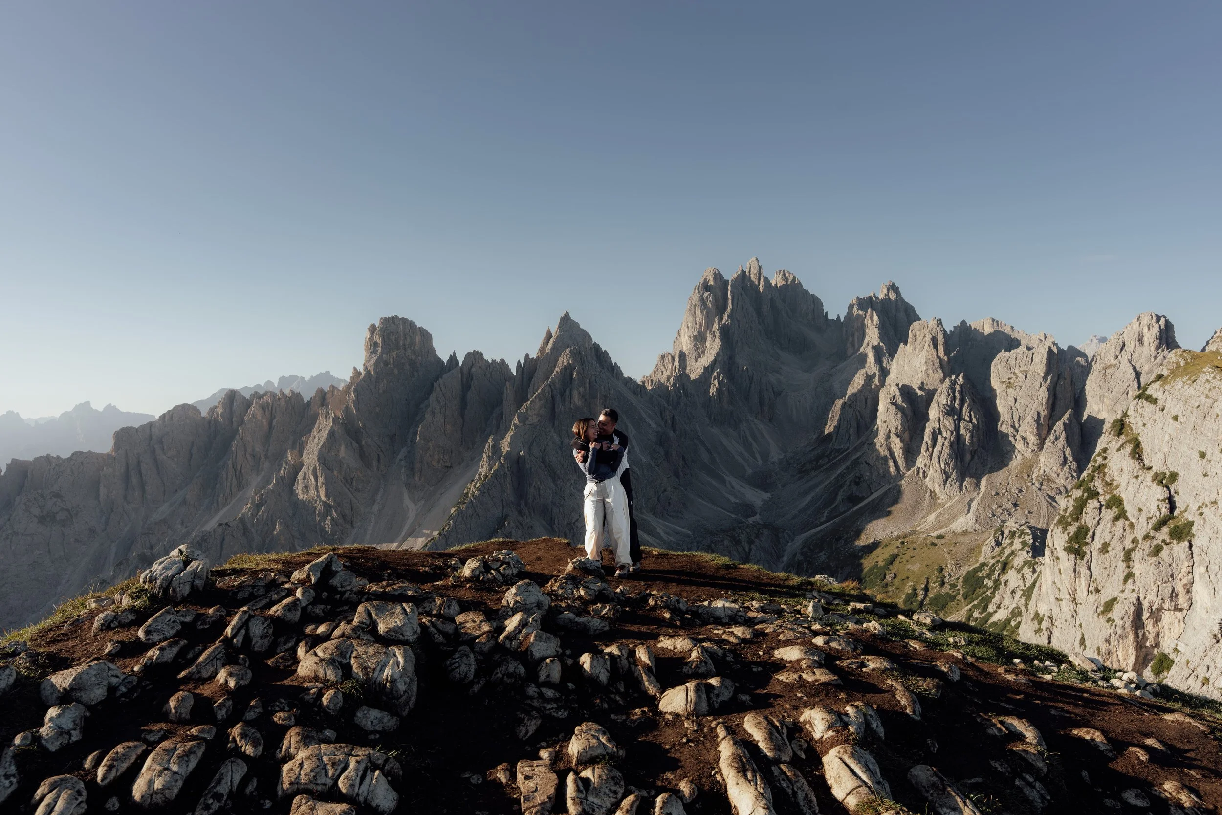 Engaged couple enjoying the sunrise at the Cadini di Misurina viewpoint in Italy.