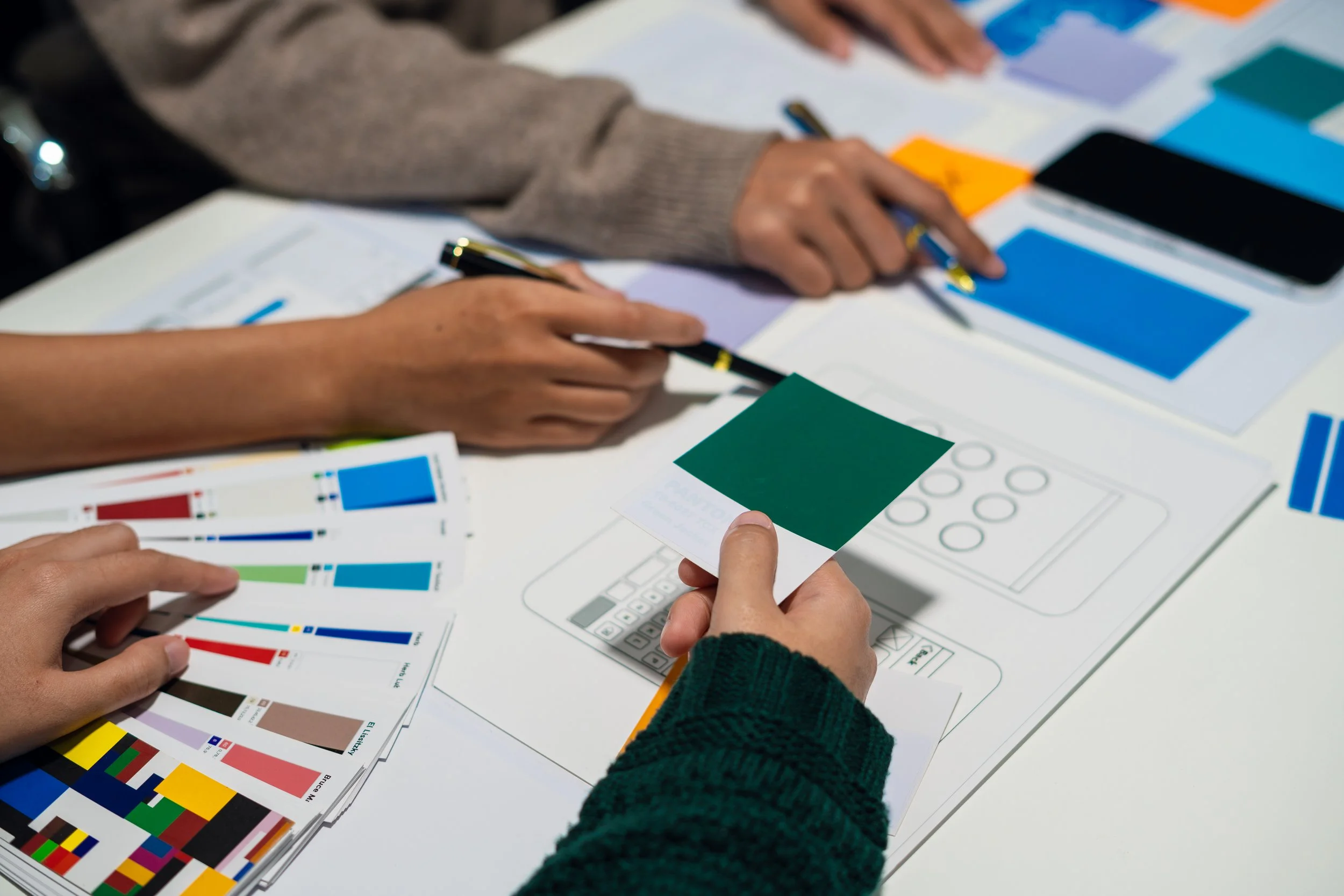 People reviewing color swatches and design sketches at a workspace.