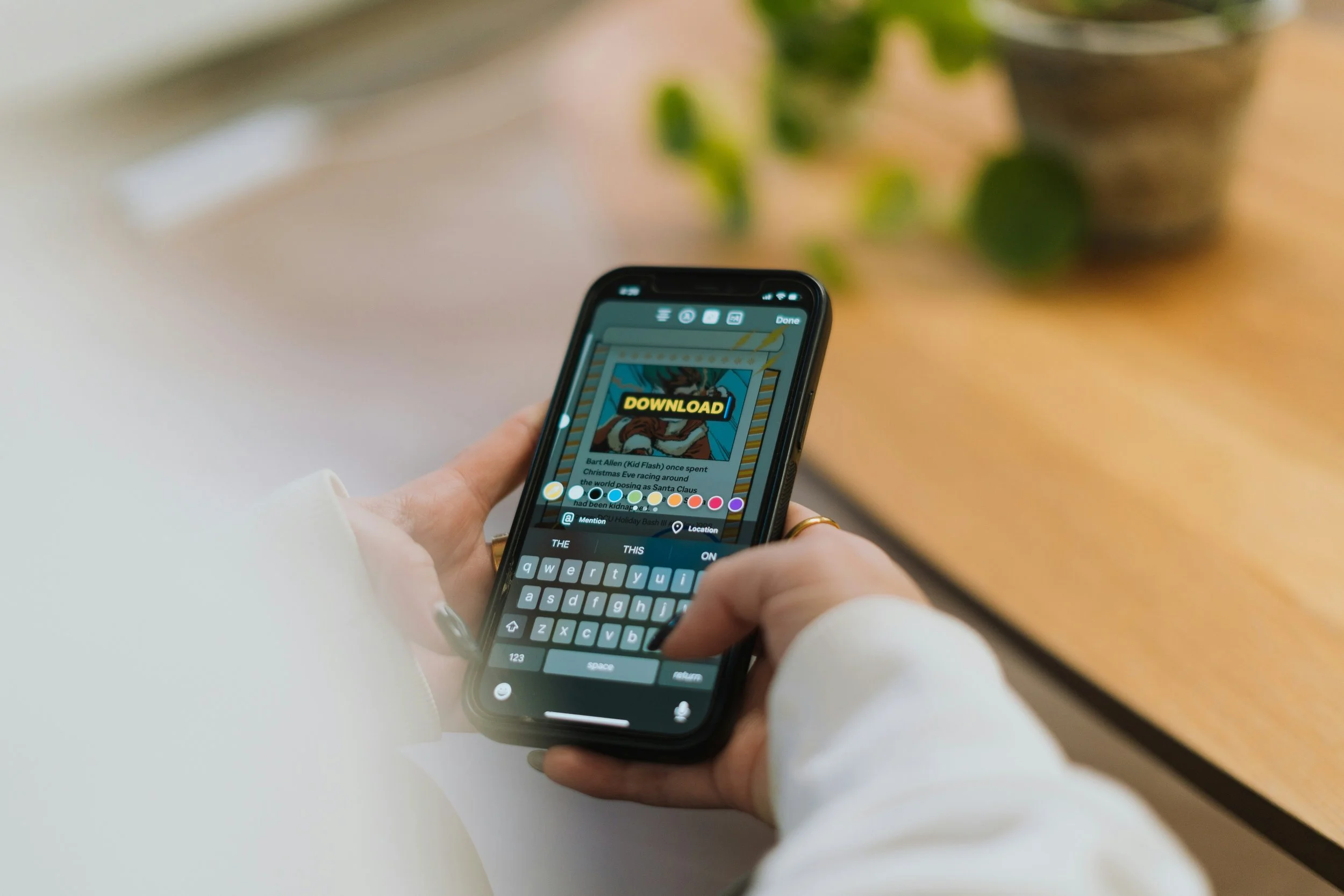 Person using a smartphone to edit a social media post with a comic-style image and the word 'DOWNLOAD' on the screen.