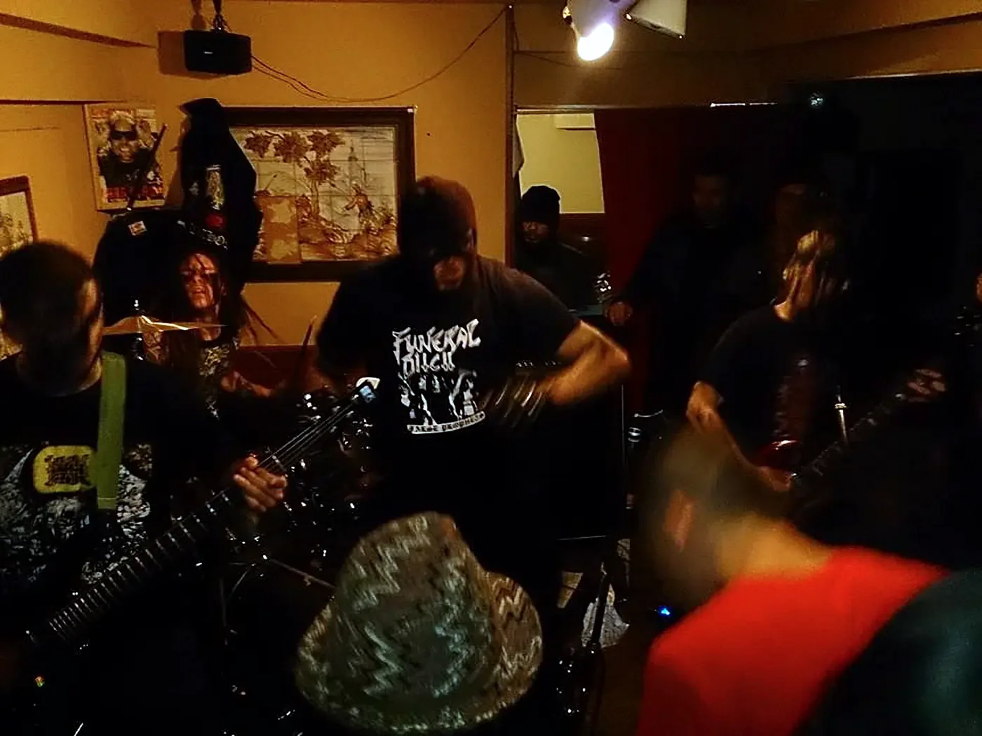 Darkcorpse performing raw black metal in a small room with fast motion and close physical intensity.