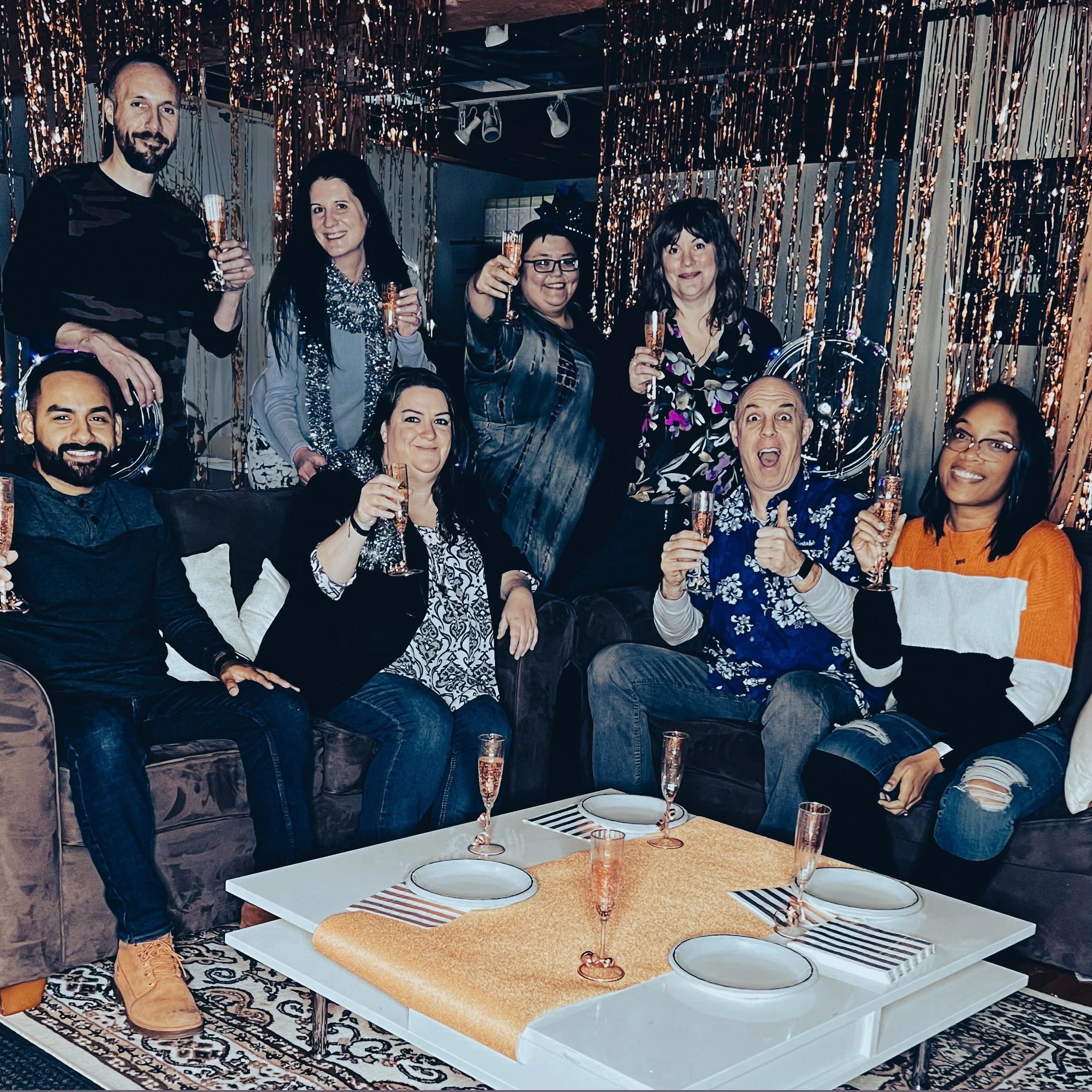 Group of nine people celebrating with champagne at party in decorated room