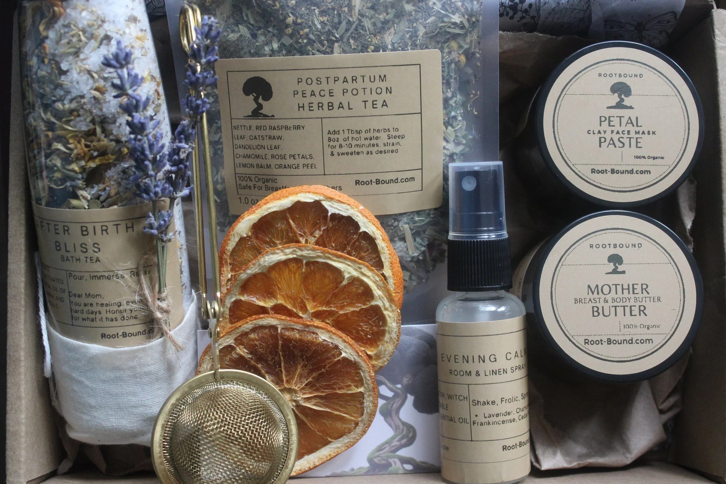 Postpartum gift set featuring a loose leaf herbal tea, bath soak,  breast and body lotion, kaolin face mask, and evening calm linen spray