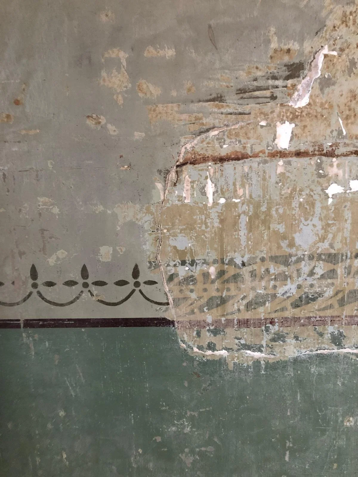 Close-up of a cracked and peeling wall or ceiling with old paint and decorative border.