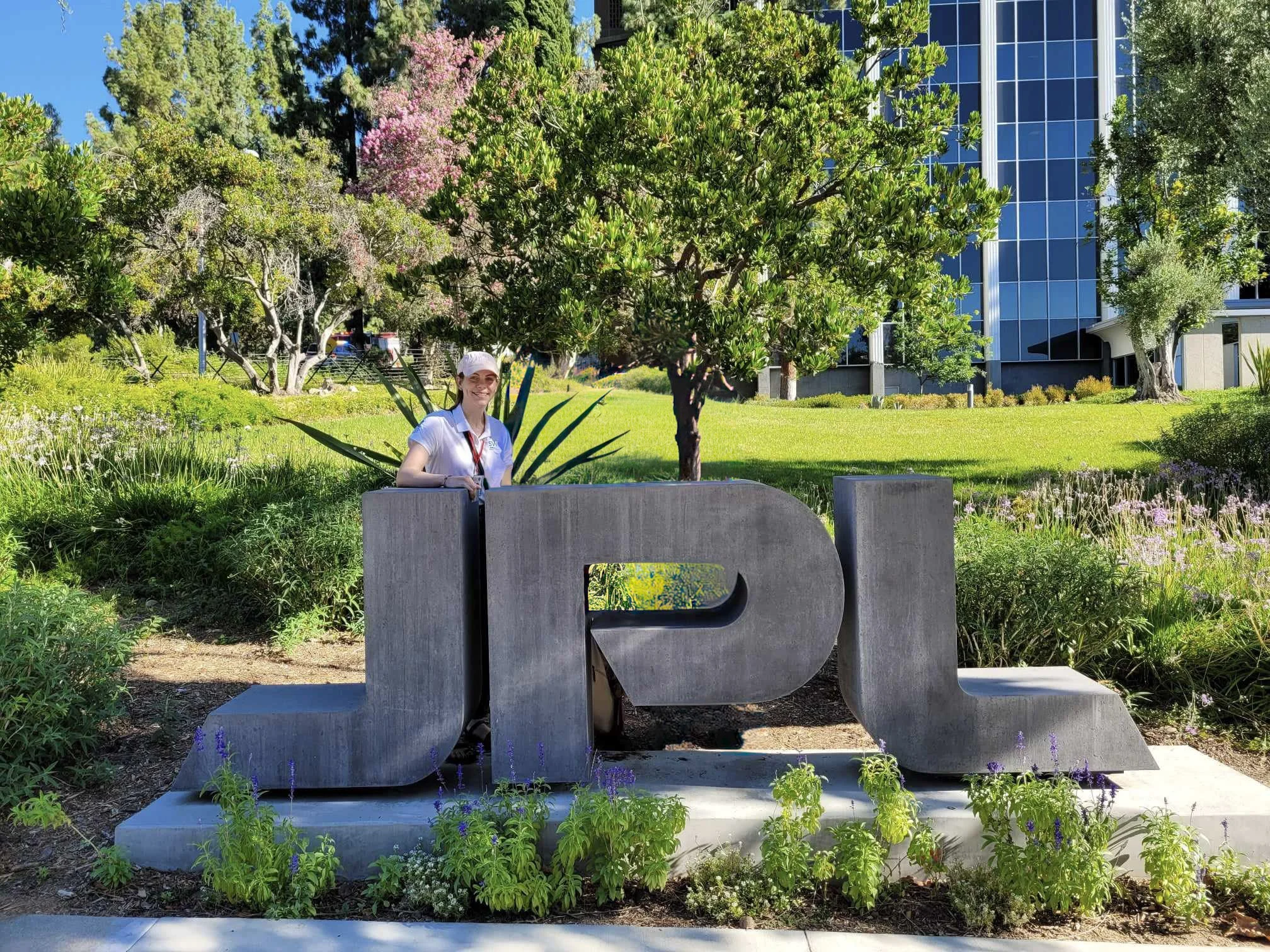 Cassie Stuurman, JPL Signal Analysis Engineer, in front of the JPL sign at NASA JPL, Pasadena, CA