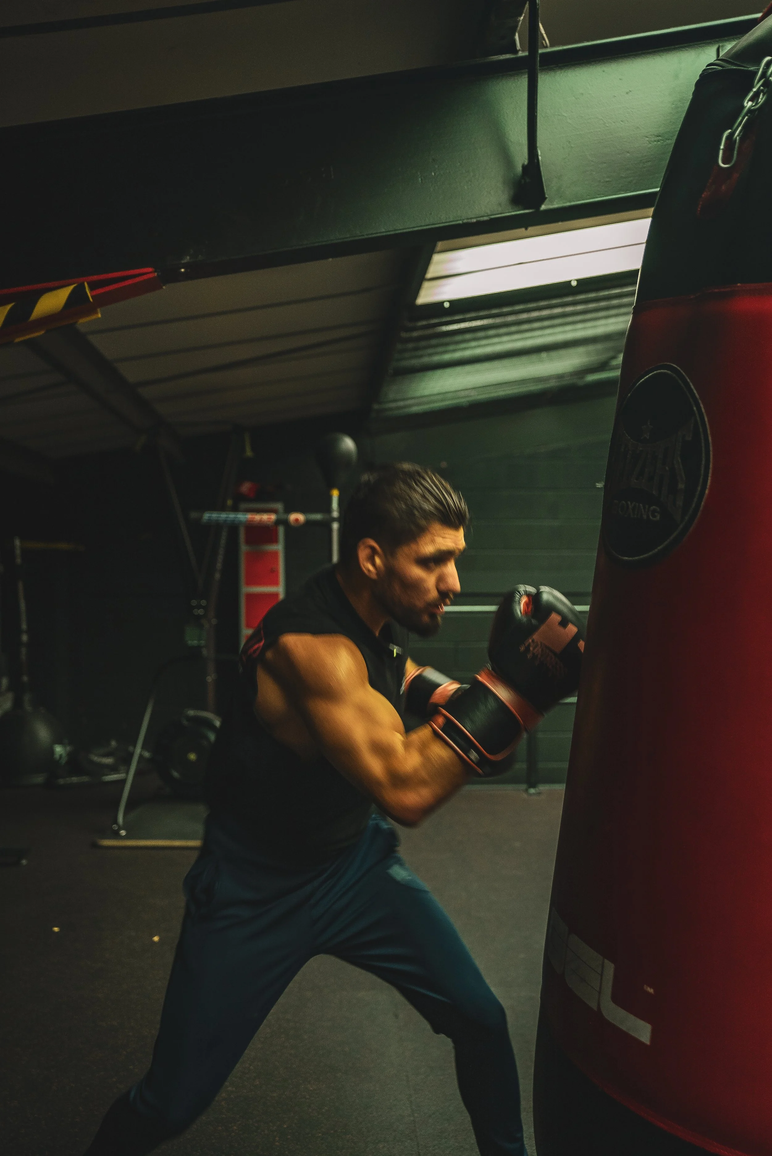 A man practicing boxing on a punching bag in a gym.