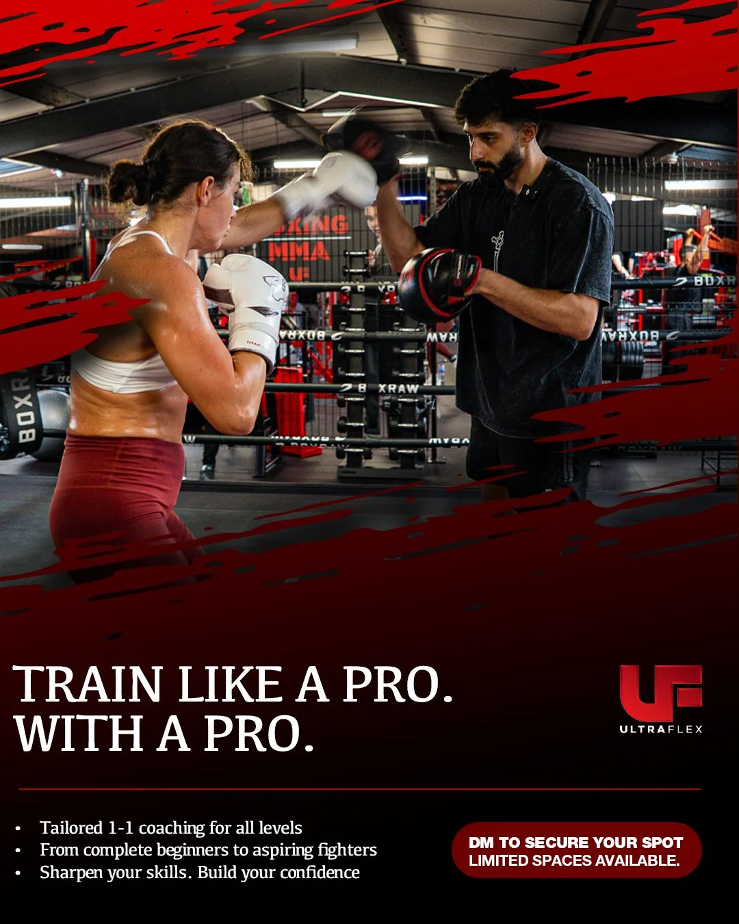 A female boxer training with a male coach in a gym. The coach is holding focus mitts while the boxer practices punching. The gym has boxing equipment and a ring in the background.