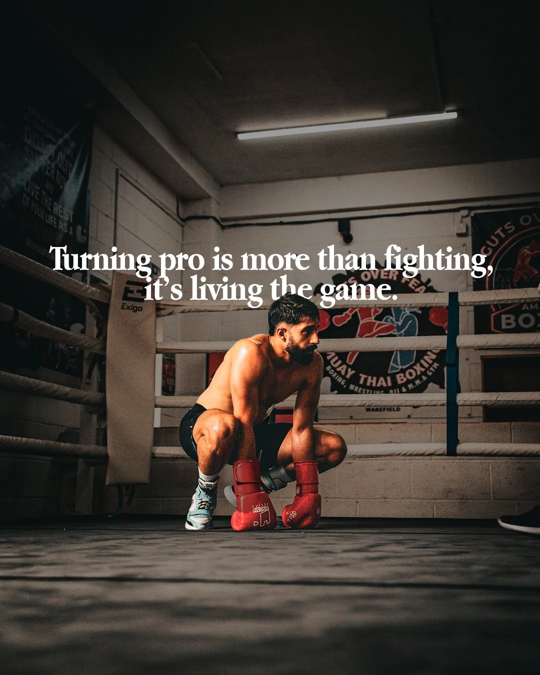 A boxer squatting in a boxing ring, wearing boxing gloves and athletic shorts, with a focused expression. The words overlayed say: 'Turning pro is more than fighting, it's living the game.'