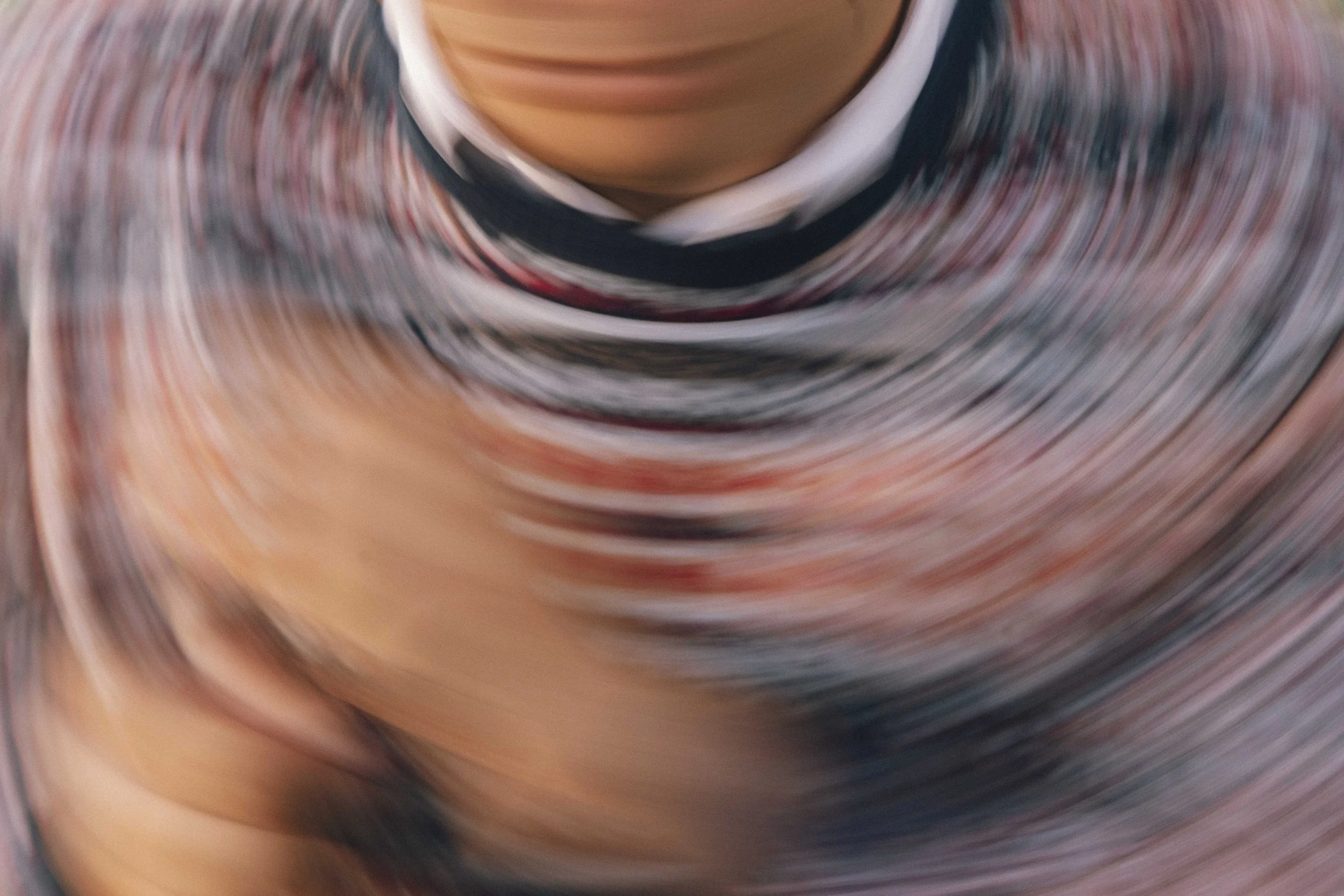 A close-up of a person wearing a colorful, patterned shirt, with a blurred swirl effect.