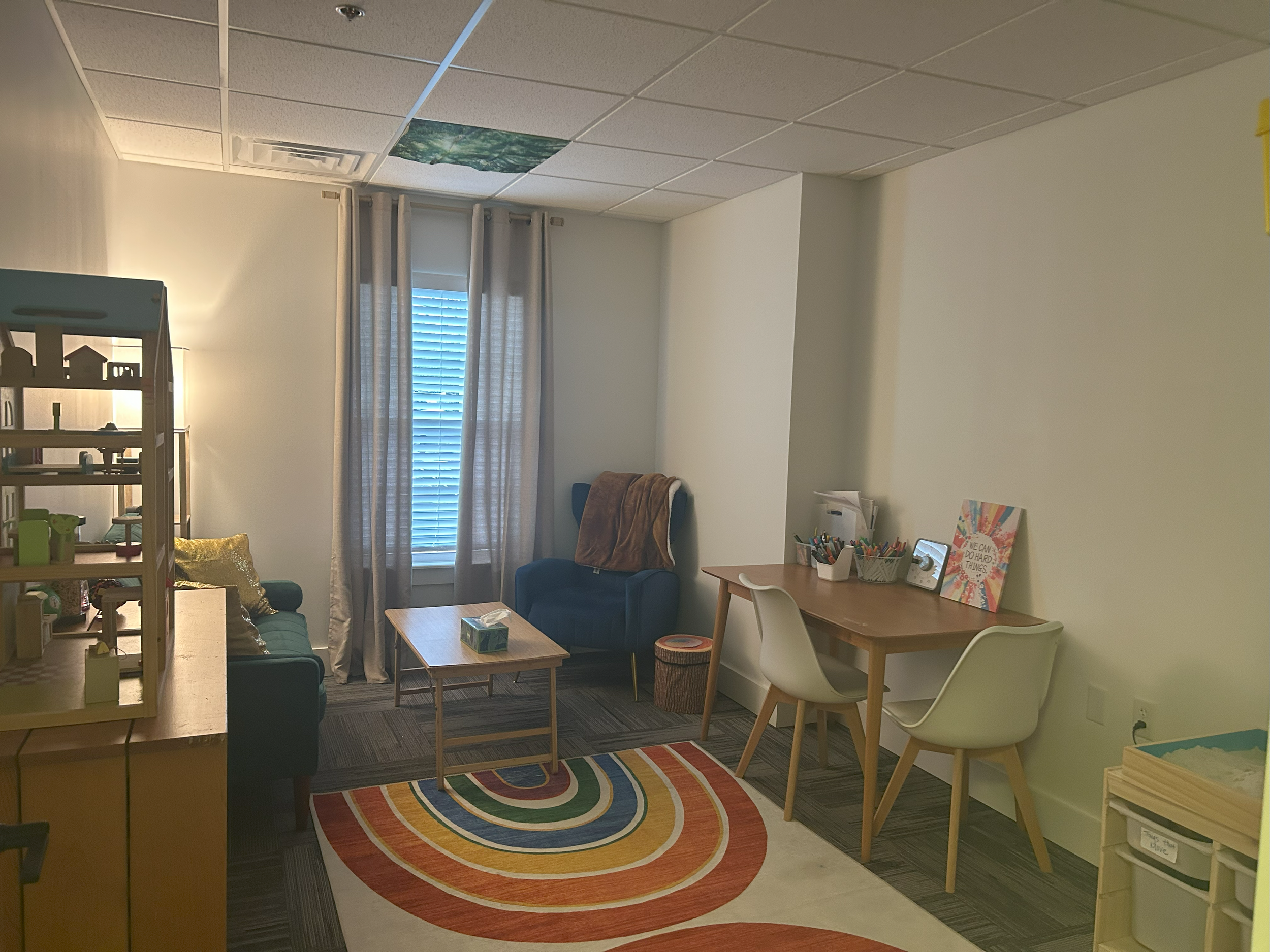 office with rainbow rug, table with chairs and coloring activities, chair, couch, and coffee table