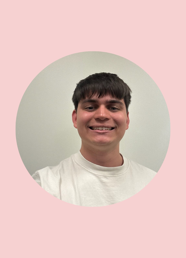 A young man taking a selfie in front of a plain wall, with a pink circular background around his photo.
