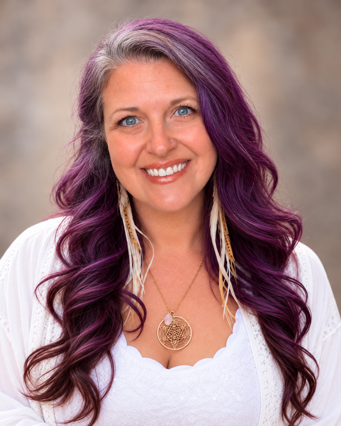 Heather Star with purple hair, wearing a large brown hat and a floral embroidered black dress, standing outdoors near a river with green trees and a blue sky in the background.