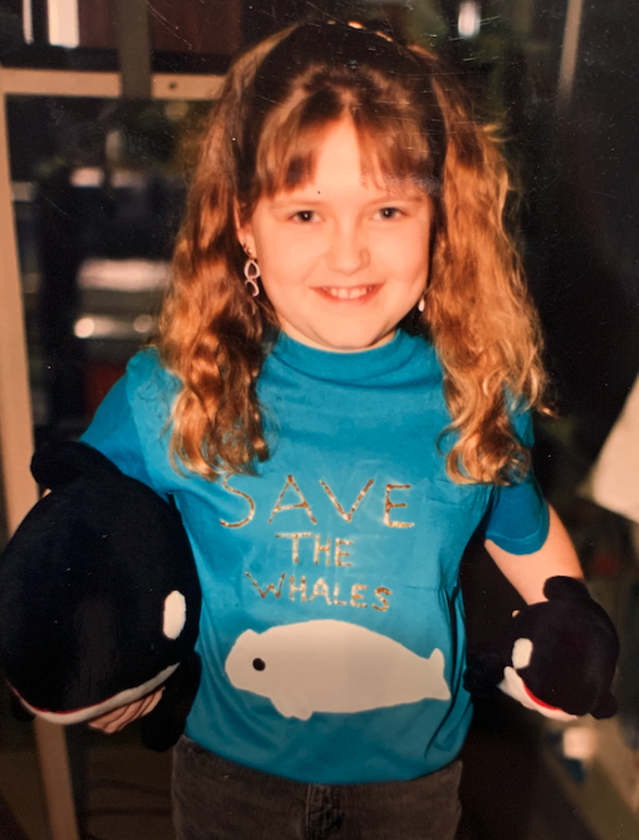 Young teen wearing a "SAVE THE WHALES" t-shirt holding plush orcas