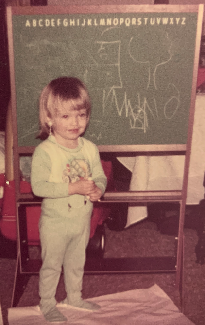 Toddler playing "teacher" with scribbles on a chalkboard