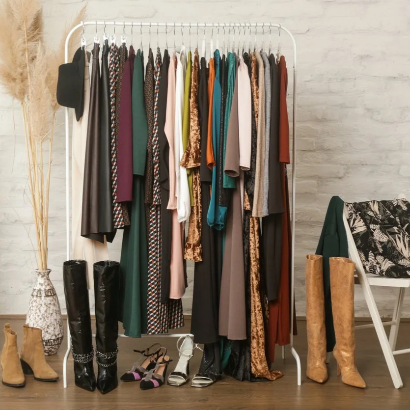 Curated outfits on a clothing rack with boots and heels for personal shopping and styling.