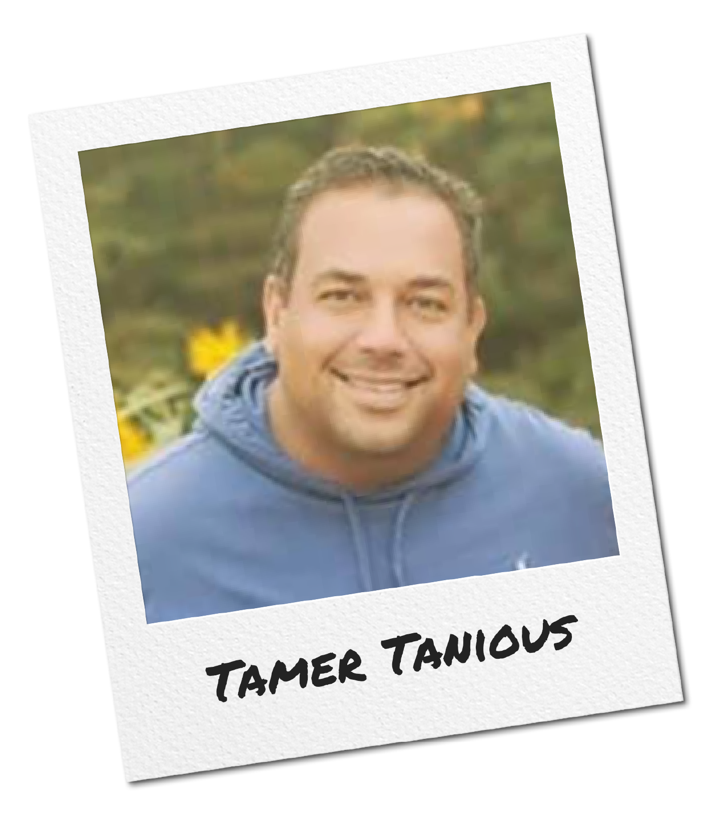A smiling man in a blue hoodie outdoors with a blurred background of trees and flowers, labeled 'Tamer Tanious'.