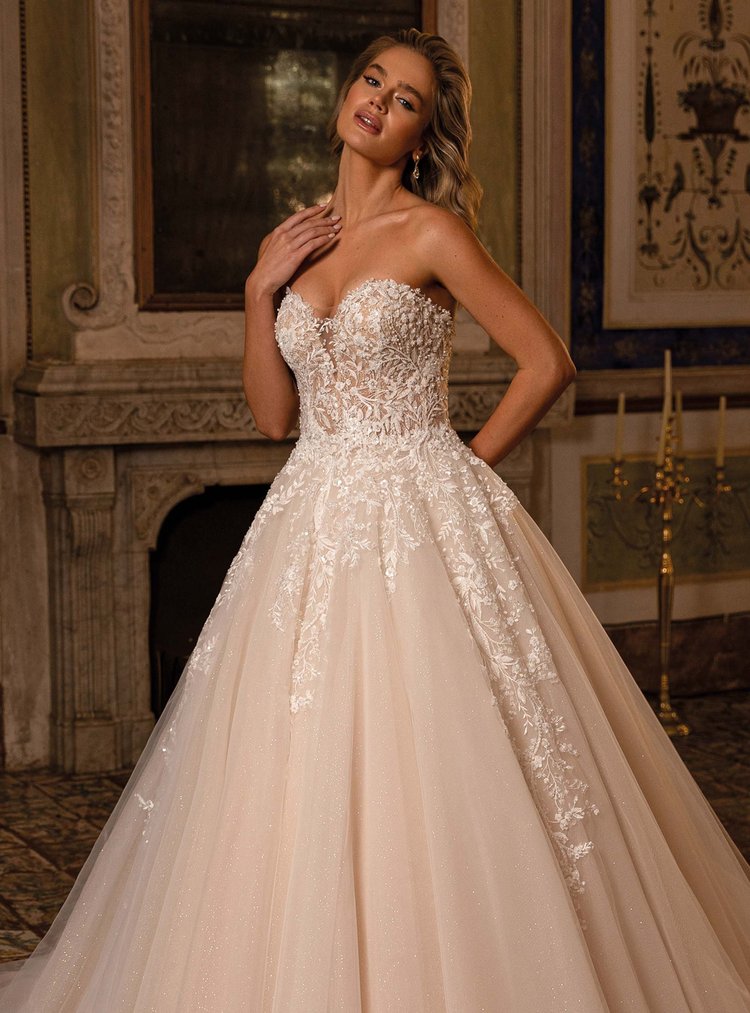 Frau in einem eleganten weißen Brautkleid mit Lace und Tüll in einem historischen Raum mit Kamin und Gemälden