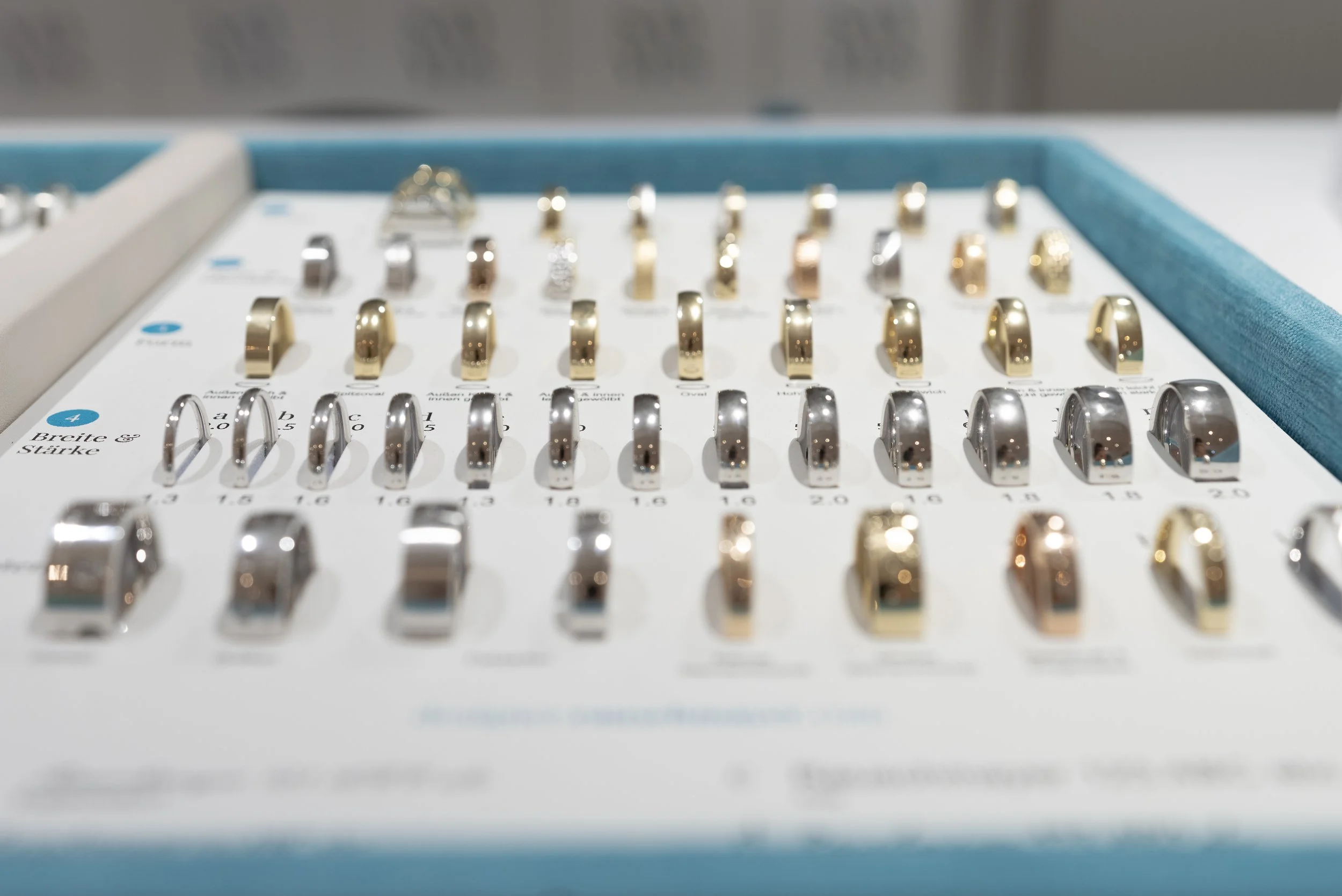 Verschiedene Ringe in einer Schmuckbox, aus Silber, Gold und Platin, angeordnet auf einem weißen Hintergrund.