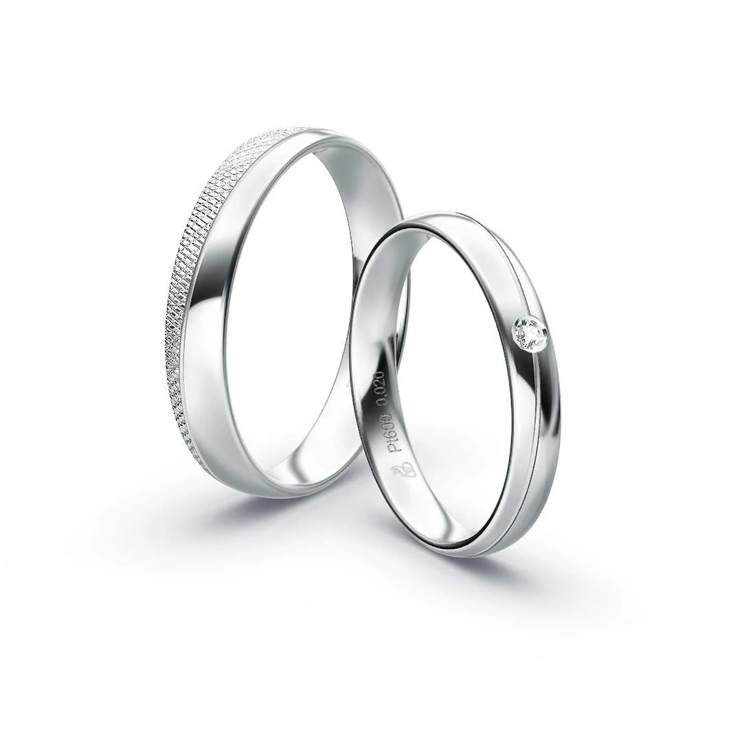Zwei silberne Eheringe, einer mit einem kleinen Diamanten, auf weißem Hintergrund