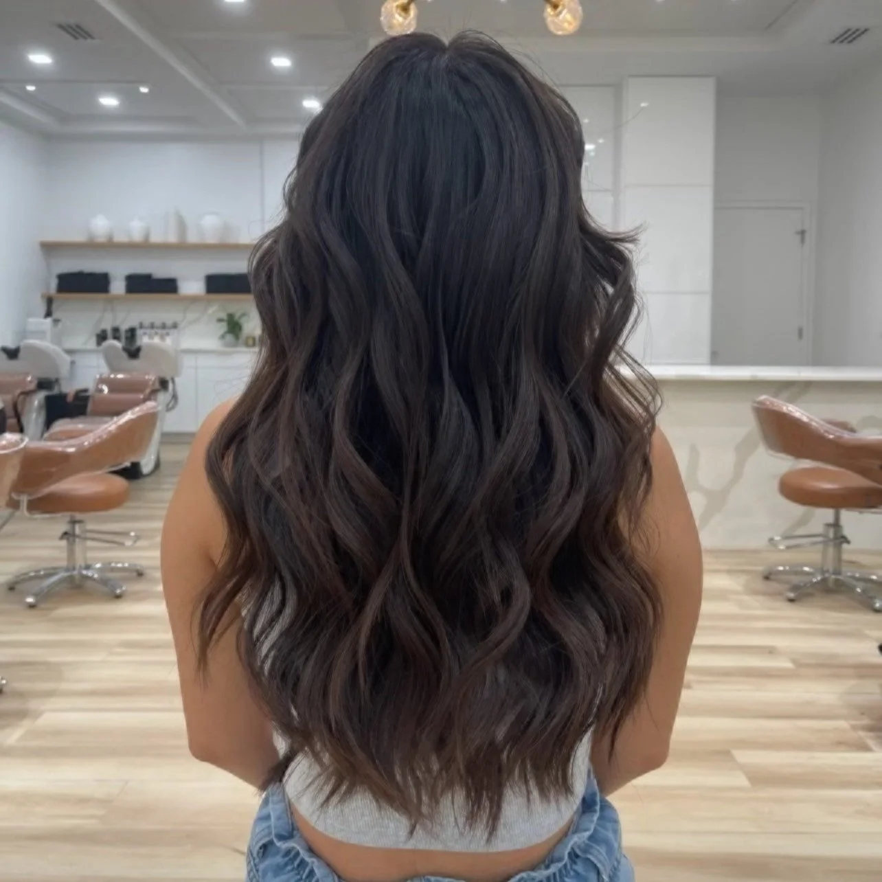 Woman with long wavy dark hair in a salon.