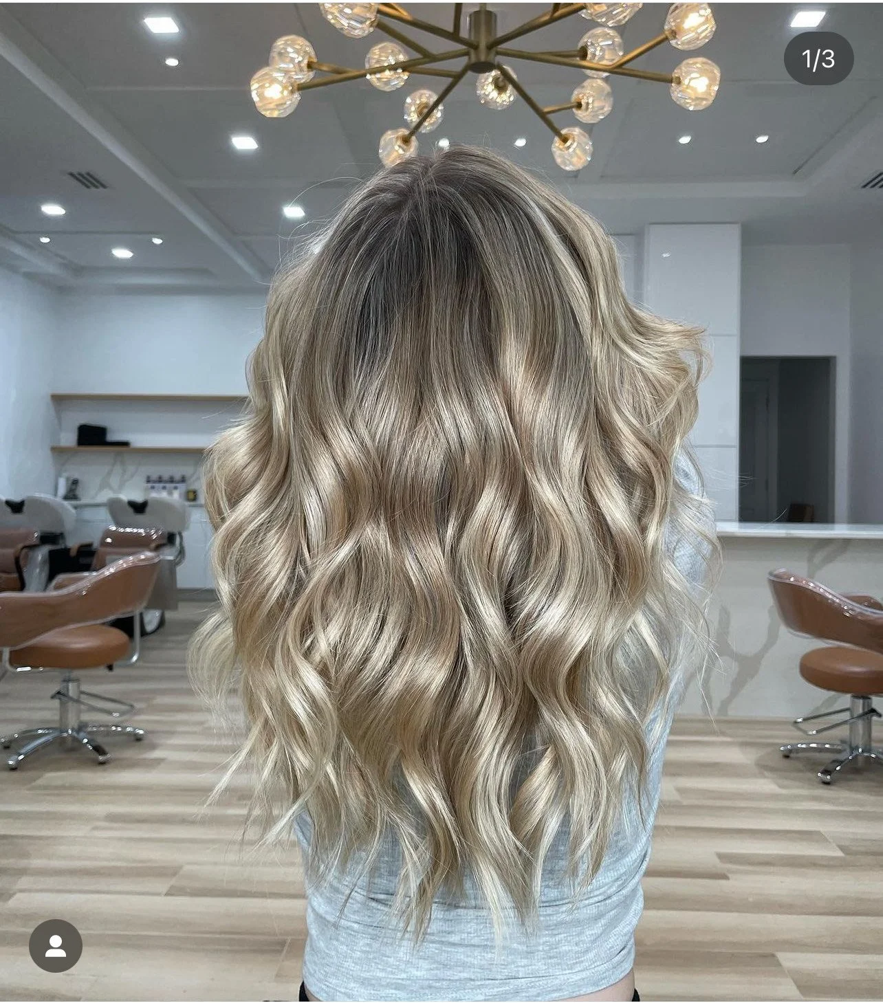 Woman with wavy blonde hair in a modern salon with chic lighting.