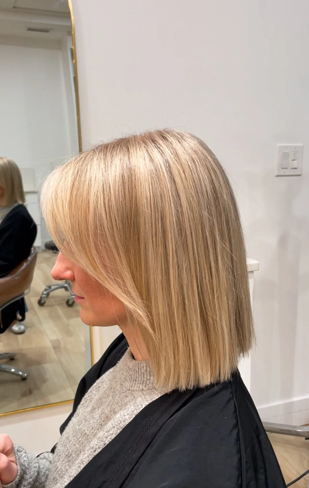 Woman with blonde shoulder-length hair getting a haircut at a salon.