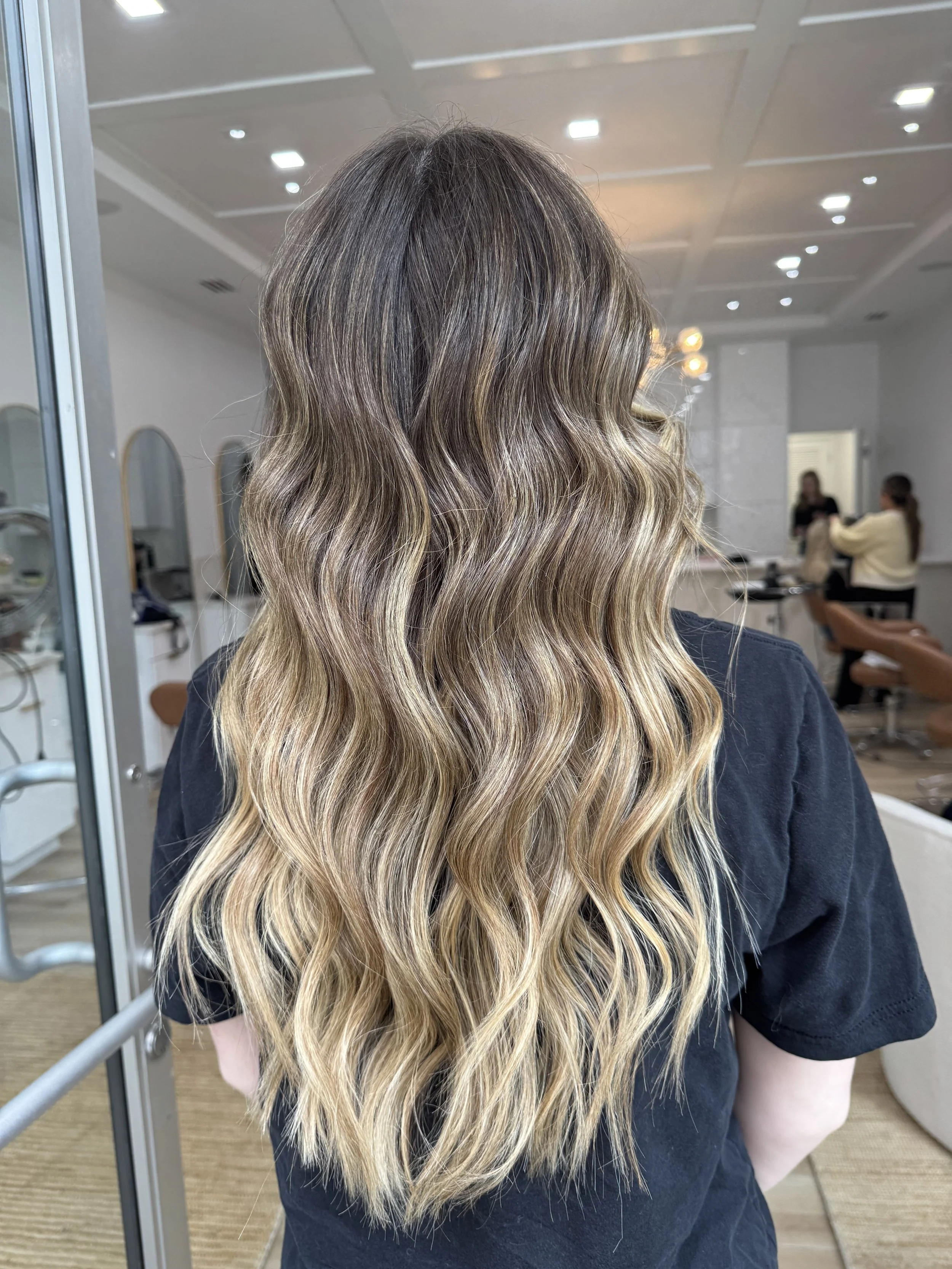 Long wavy blonde hair on a woman in a salon.