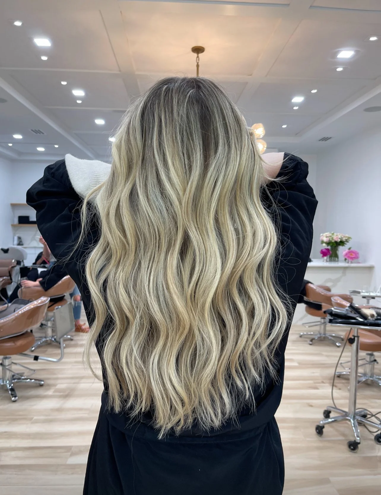 Person with long wavy blonde hair in a salon