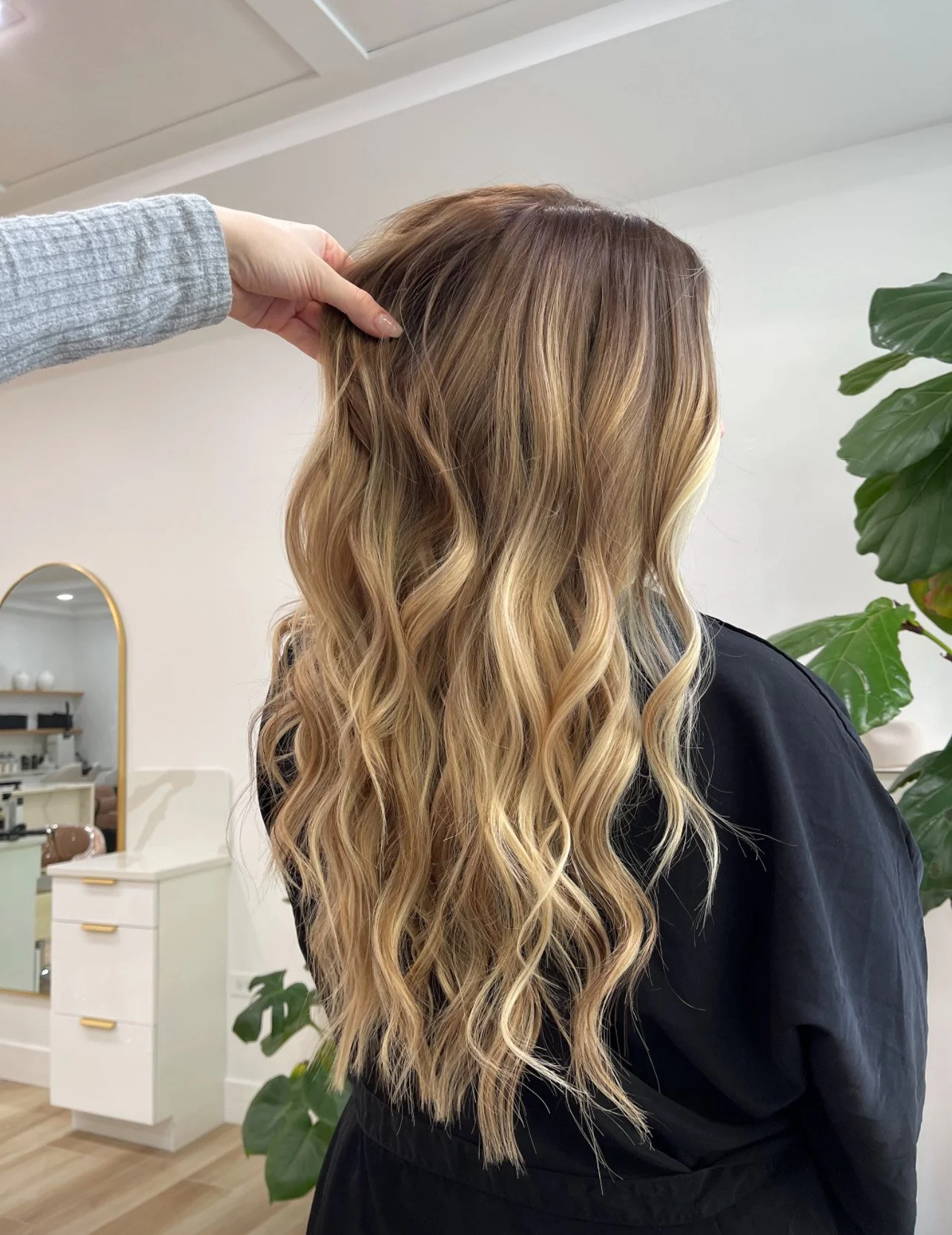 Long wavy blonde hair being styled in a salon.
