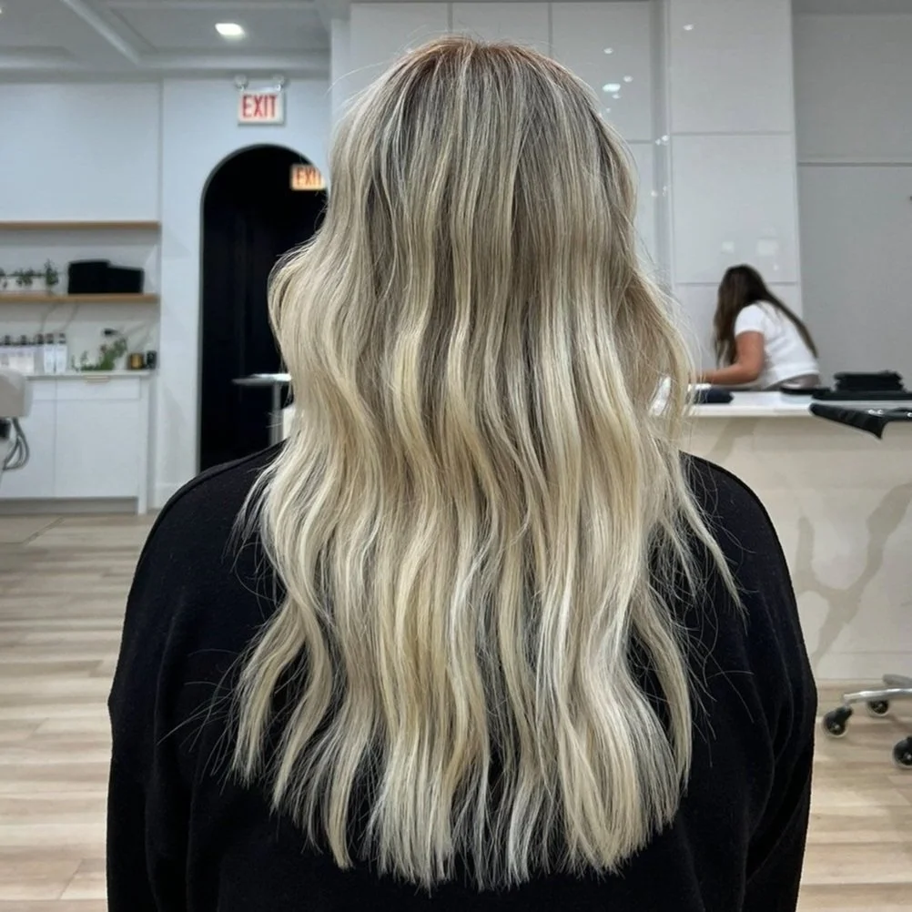 Back view of long, wavy blonde hair in a salon setting