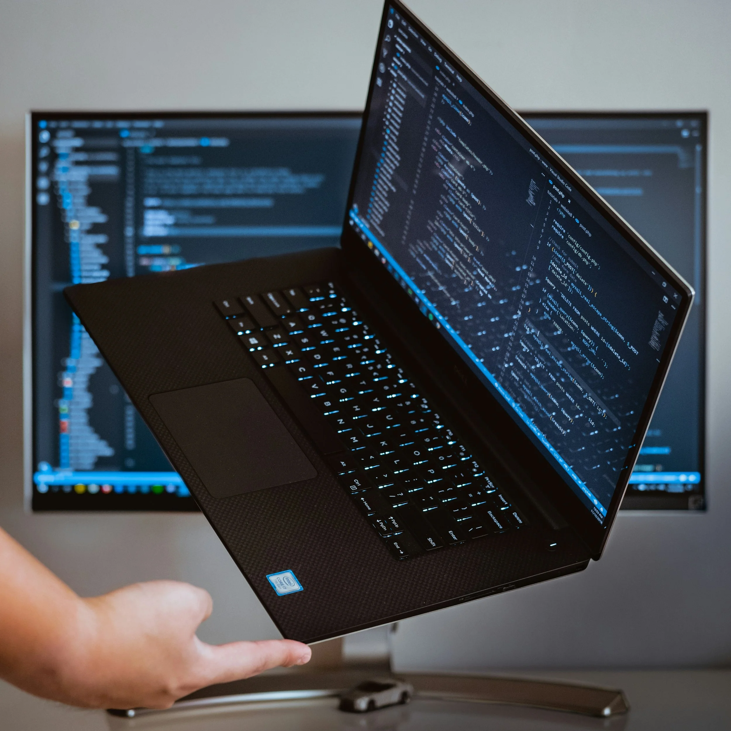 Graphic of a laptop being held up by a single index finger.