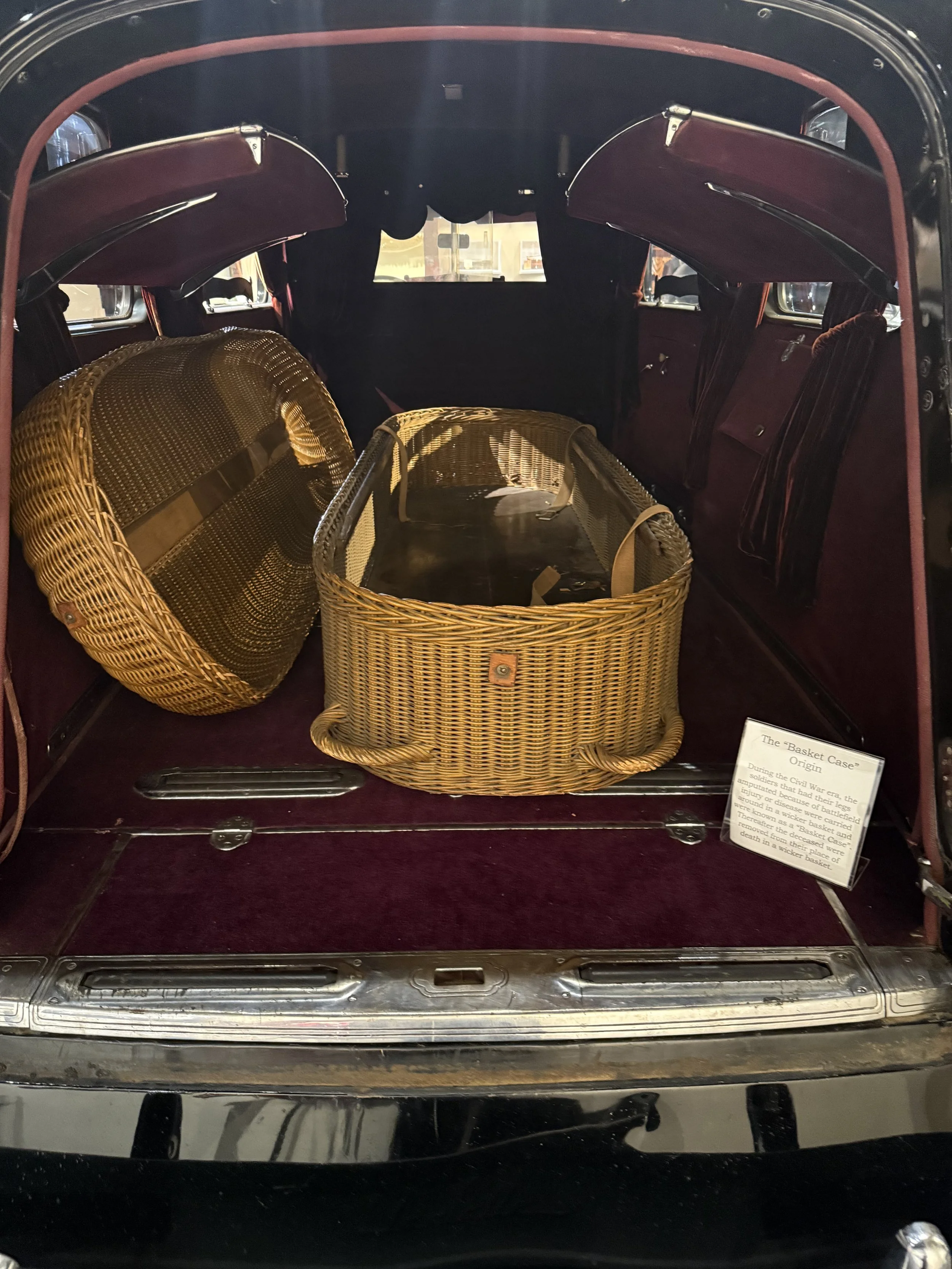 Wicker style casket in the cab of a hearse. 