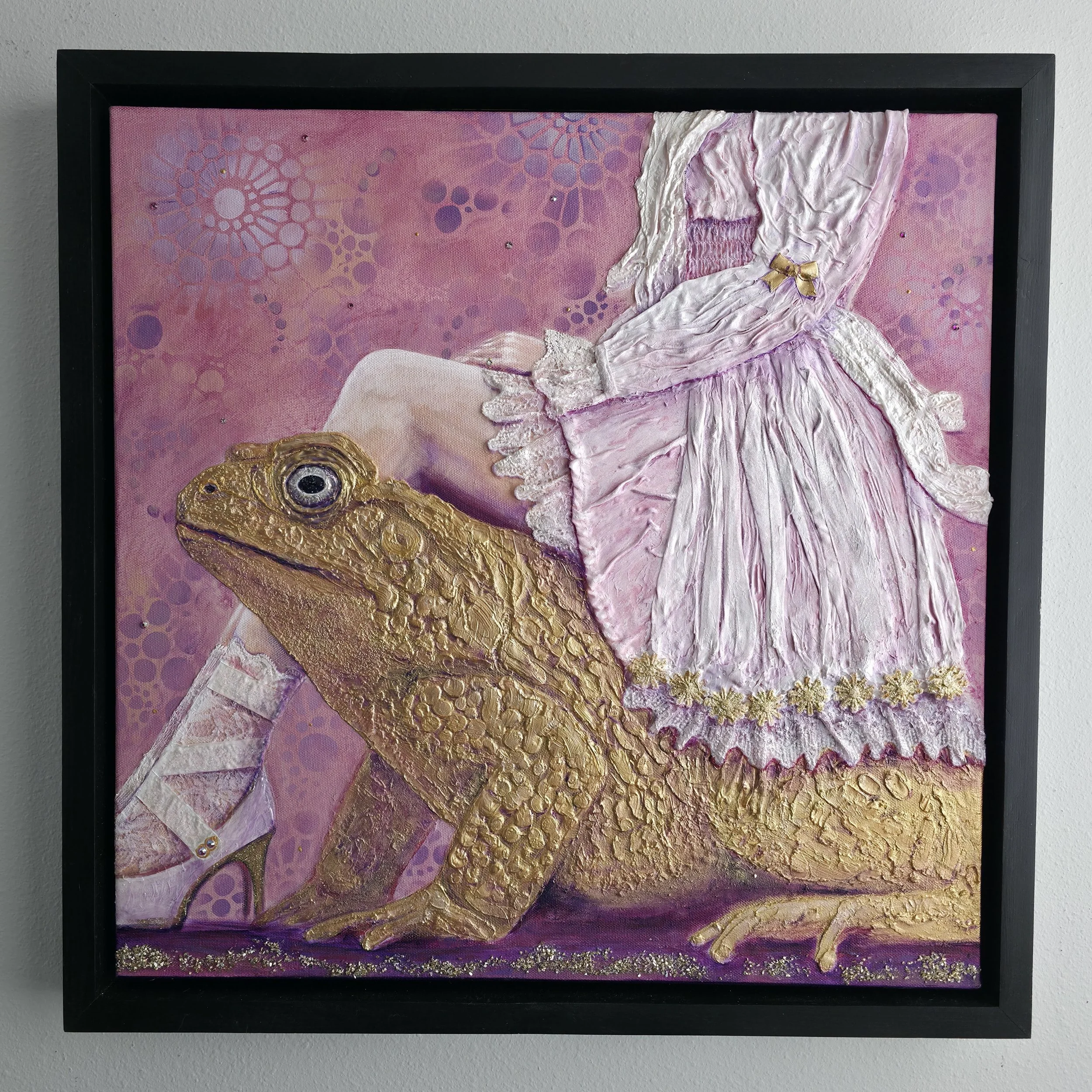Textured mixed media painting of girl wearing pink frilly dress, sitting on golden frog. Pinks and purples with gold. Framed in  handmade wooden frame.