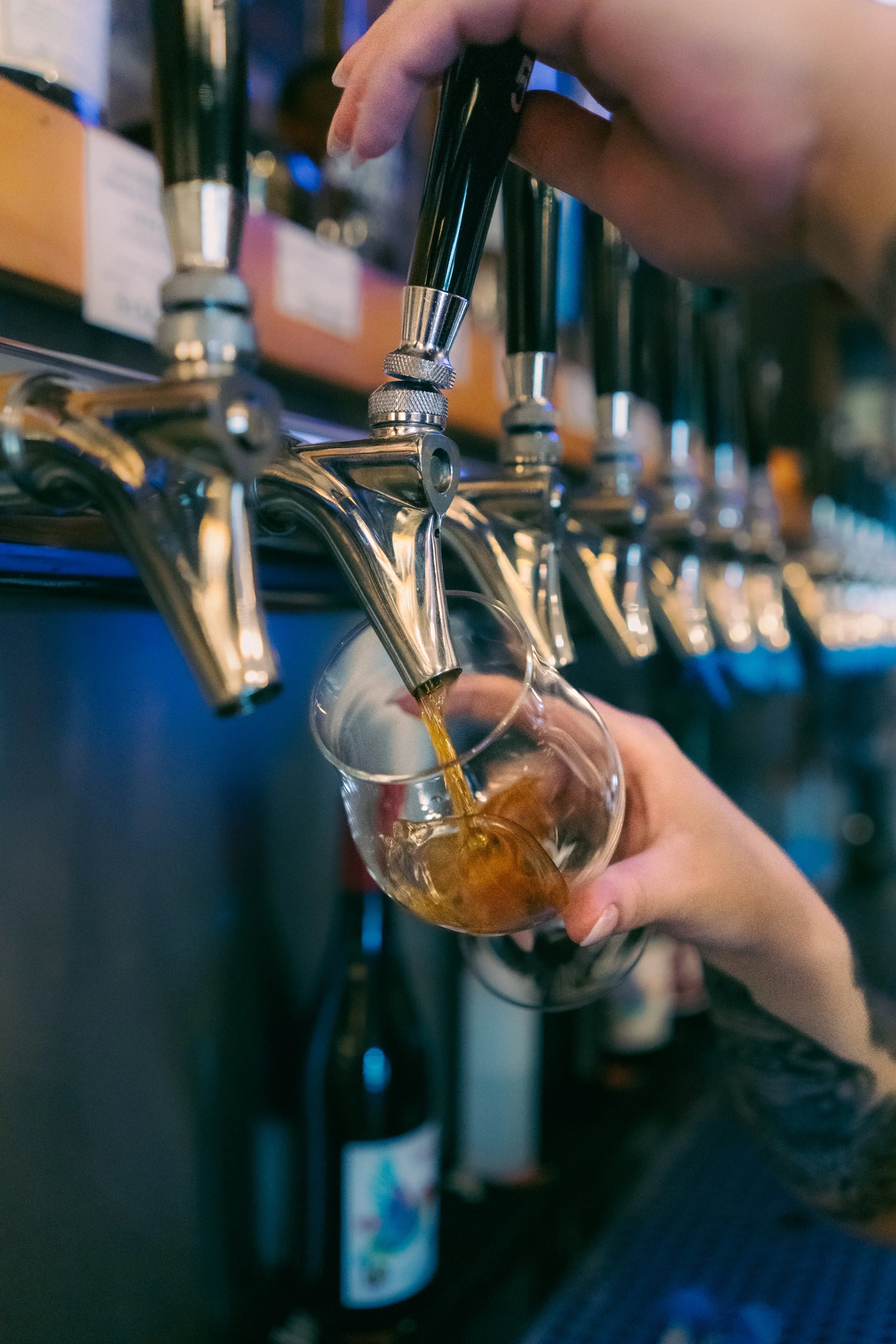 Someone pouring a dark beer from a tap into a glass at a bar.