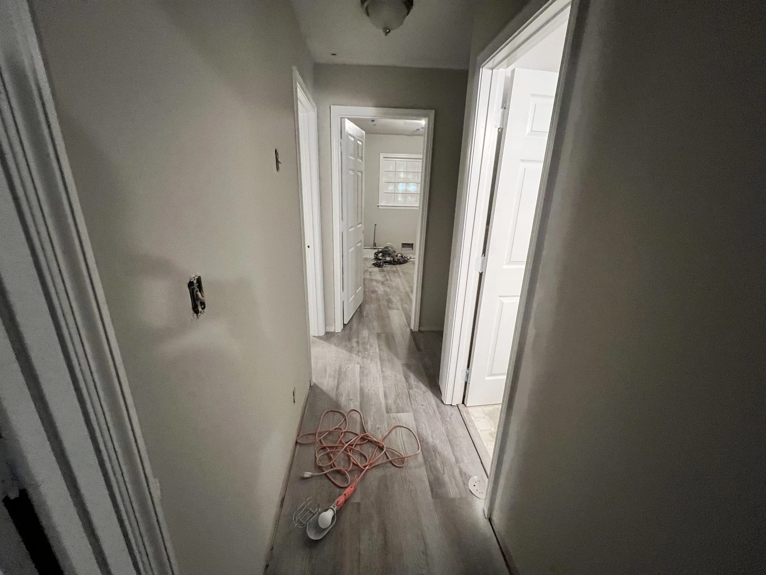Hallway with unfinished walls, open doors, and construction tools on the floor.