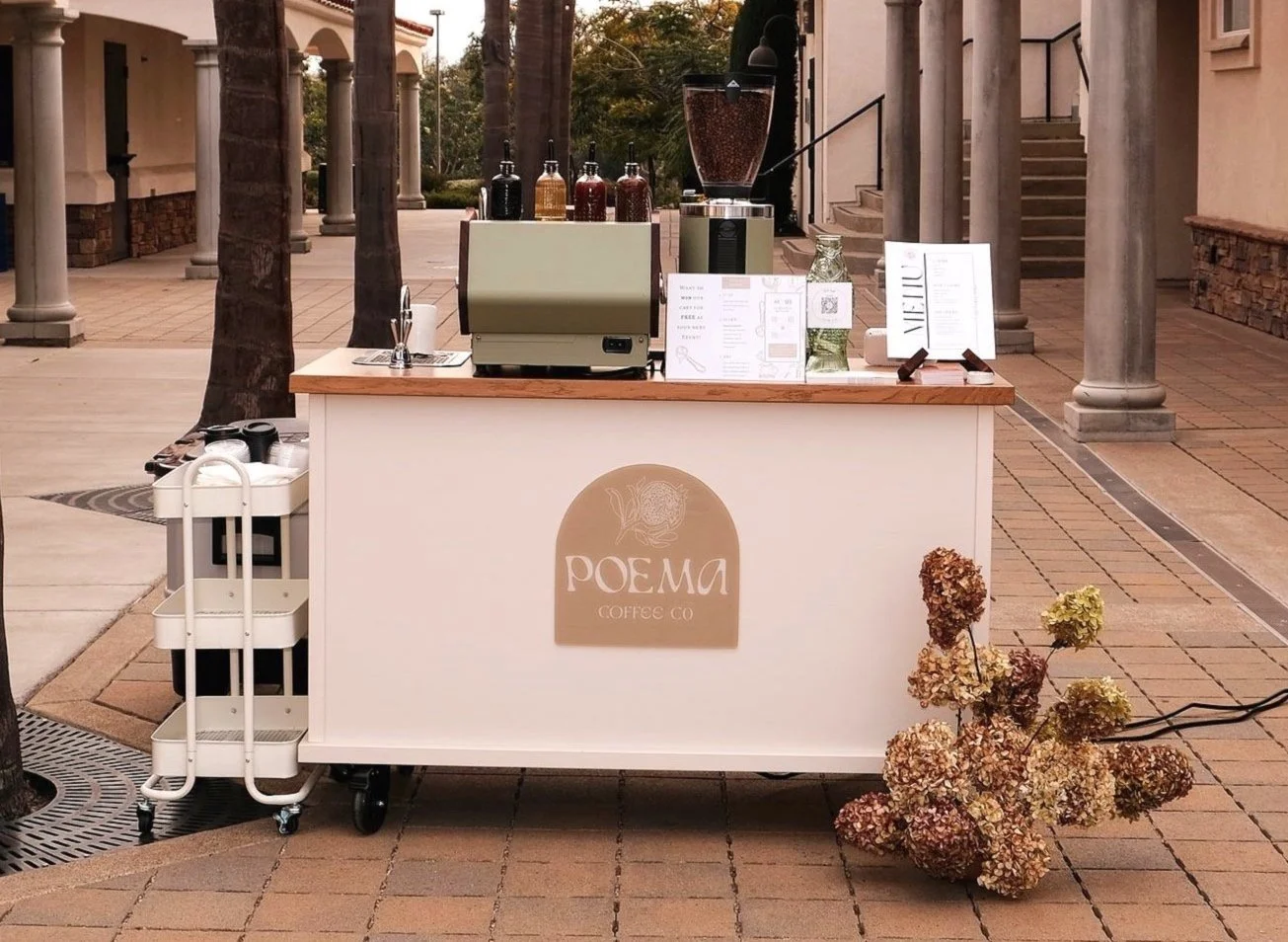 Poema Coffee Co.’s elegant mobile coffee cart set up in an outdoor venue, featuring a sleek espresso machine and curated drink menu.