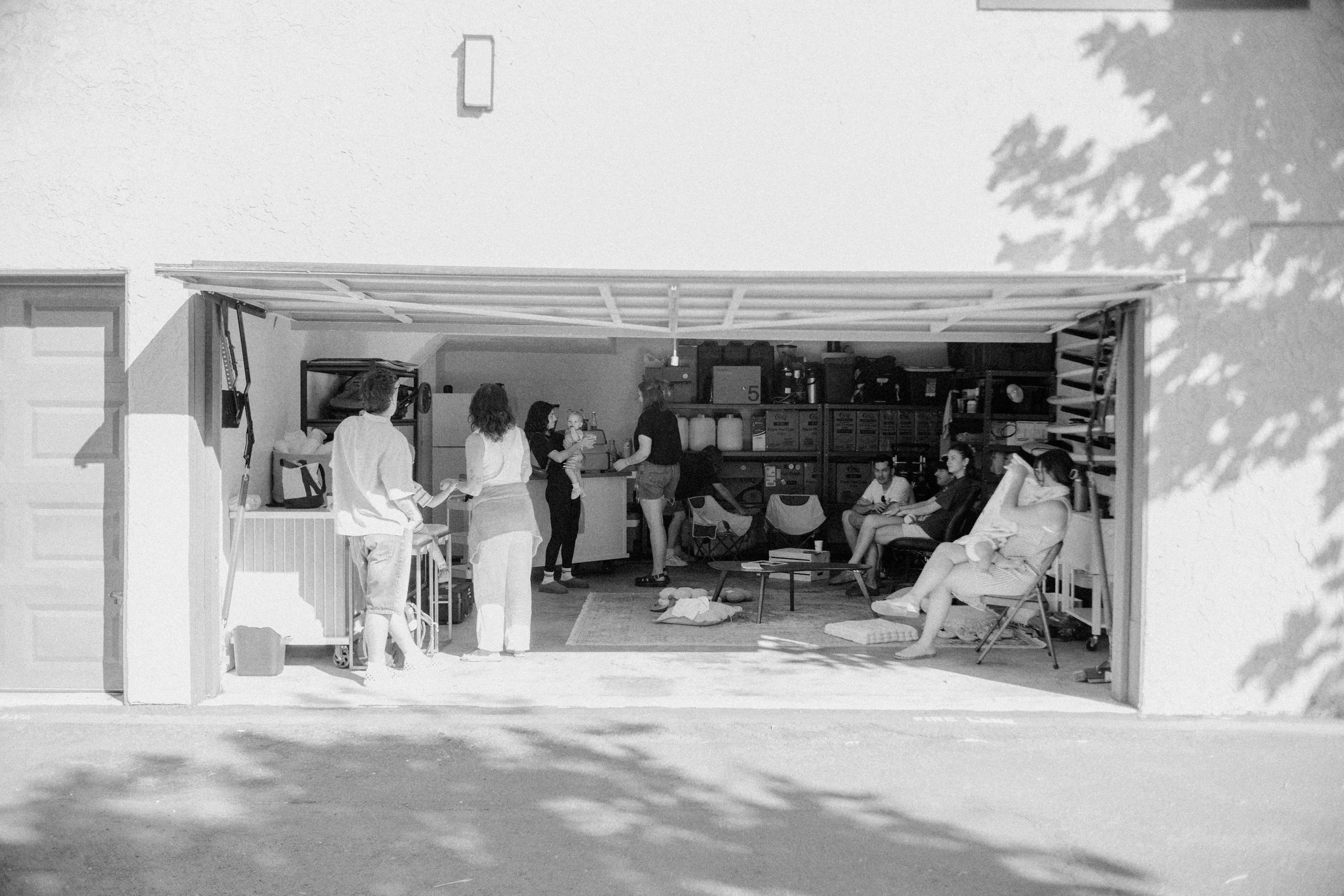 Group of people gathered in a bright garage-style coffee workspace at Poema Coffee Co, sharing community, creativity, and handcrafted coffee moments.