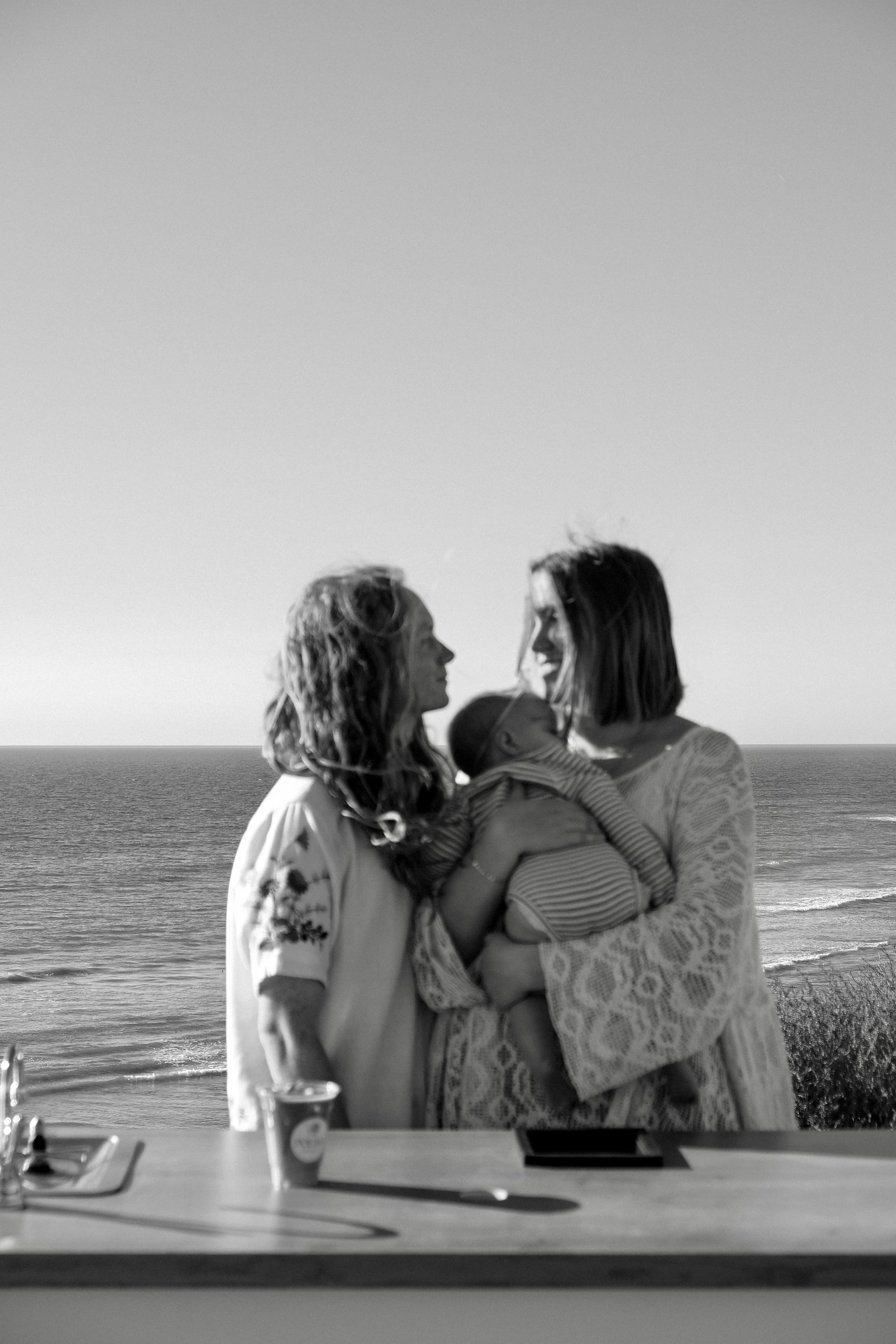 Black and white photo of guests with a baby overlooking the ocean at a Poema Coffee private event in San Diego