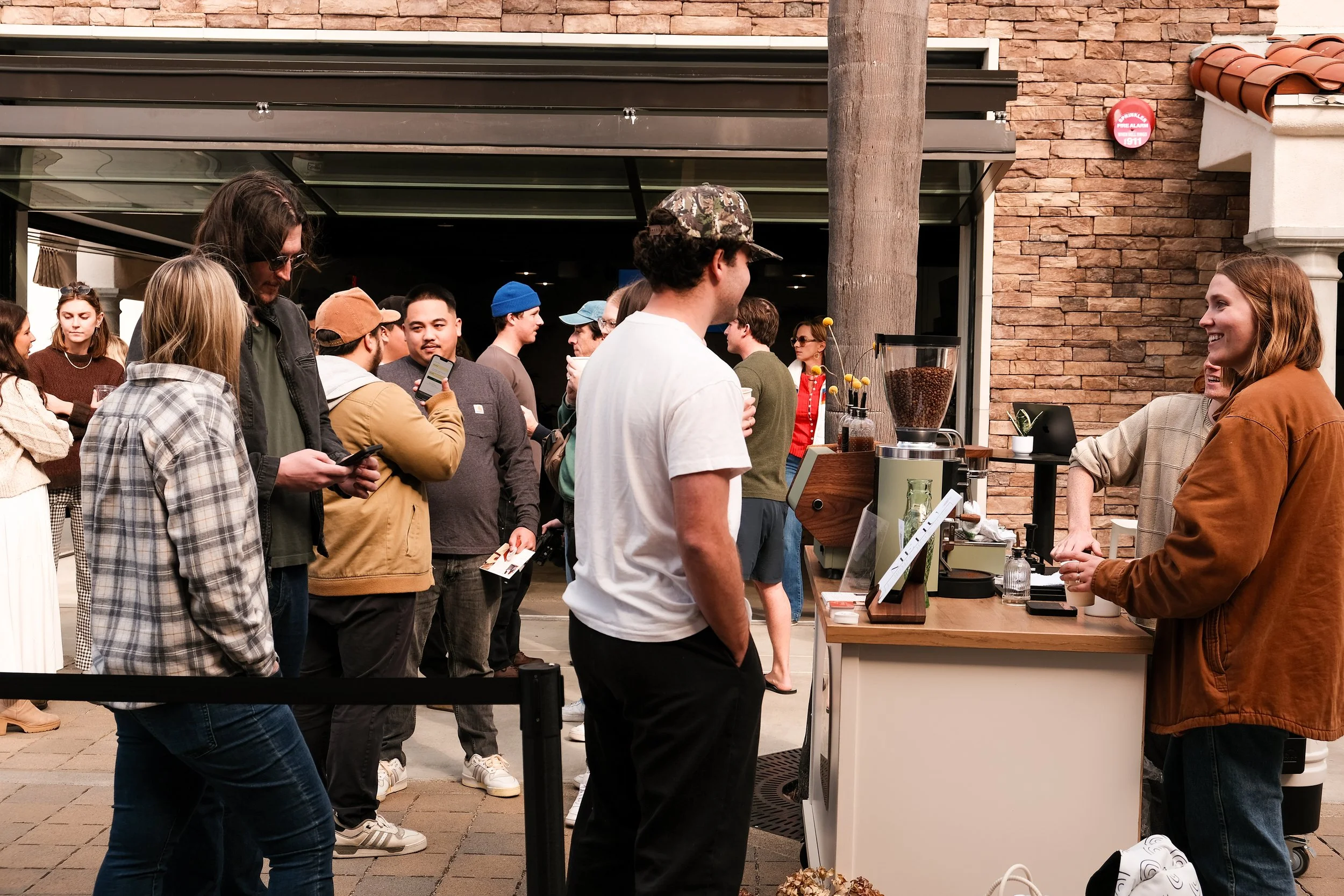 Guests lined up at a Poema mobile coffee cart for espresso drinks at an outdoor corporate event in San Diego