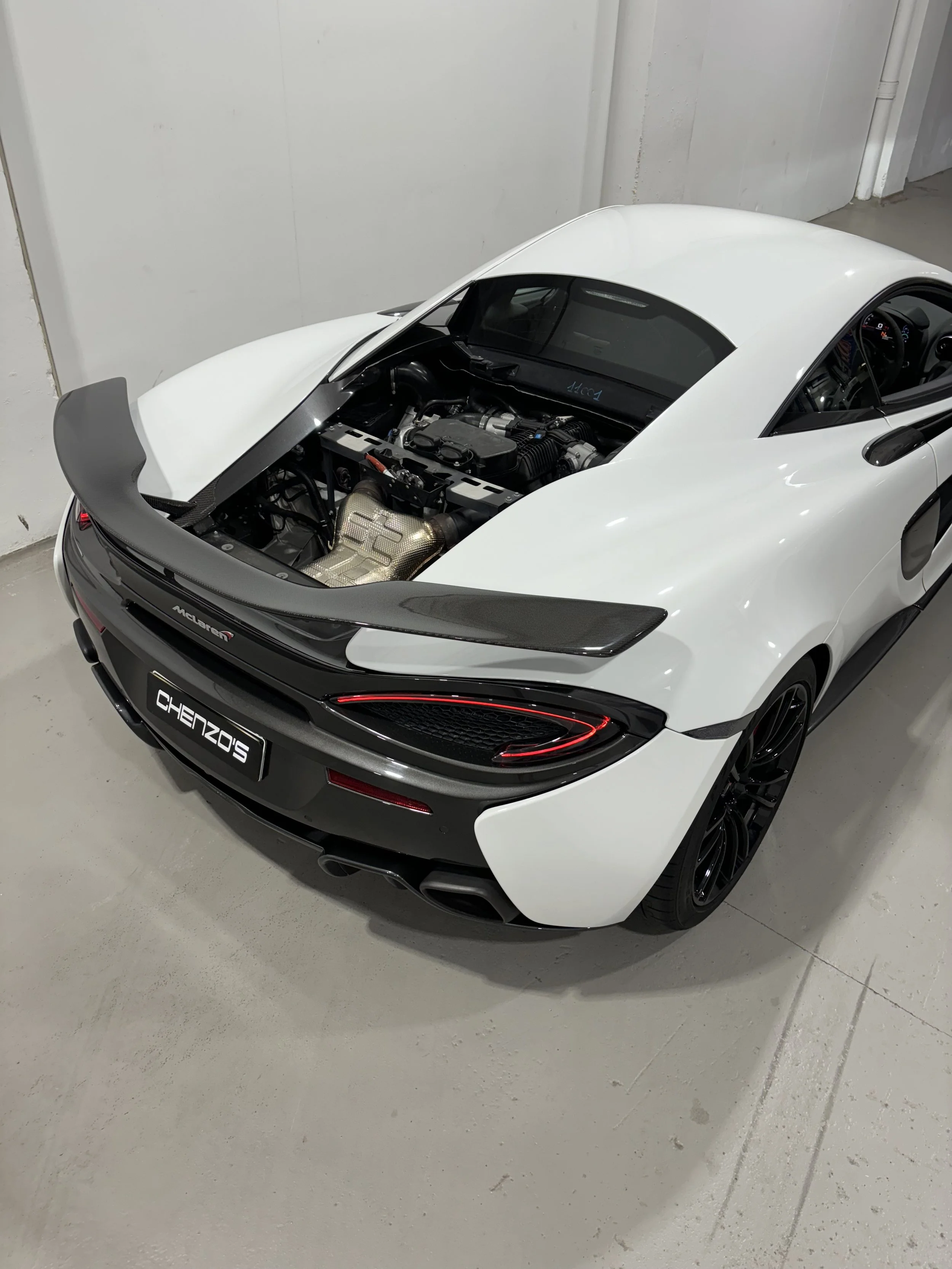 White sports car with the hood open, showing the engine.