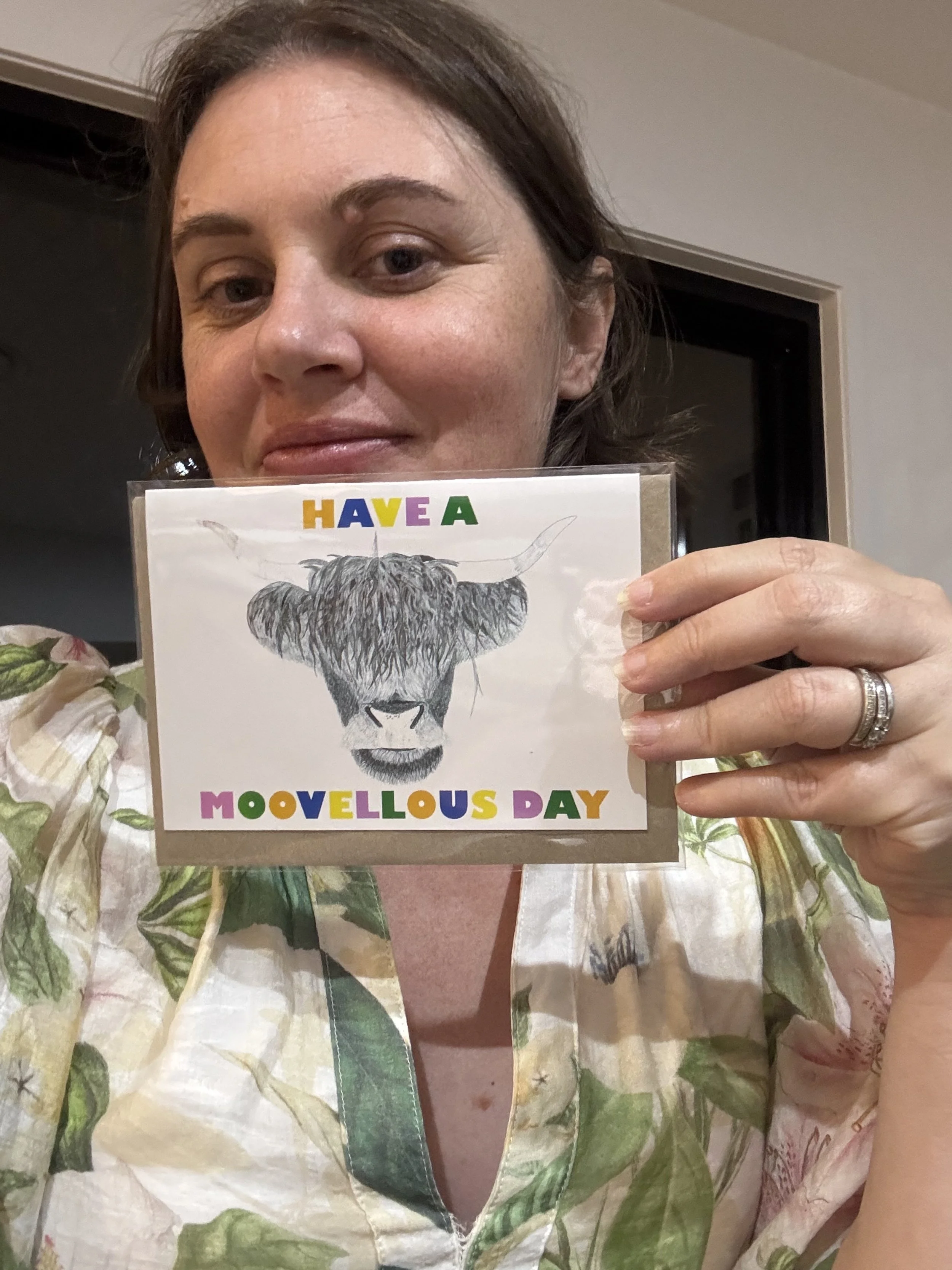 Greeting card featuring text and Ink drawing of a highland cow held by the artist