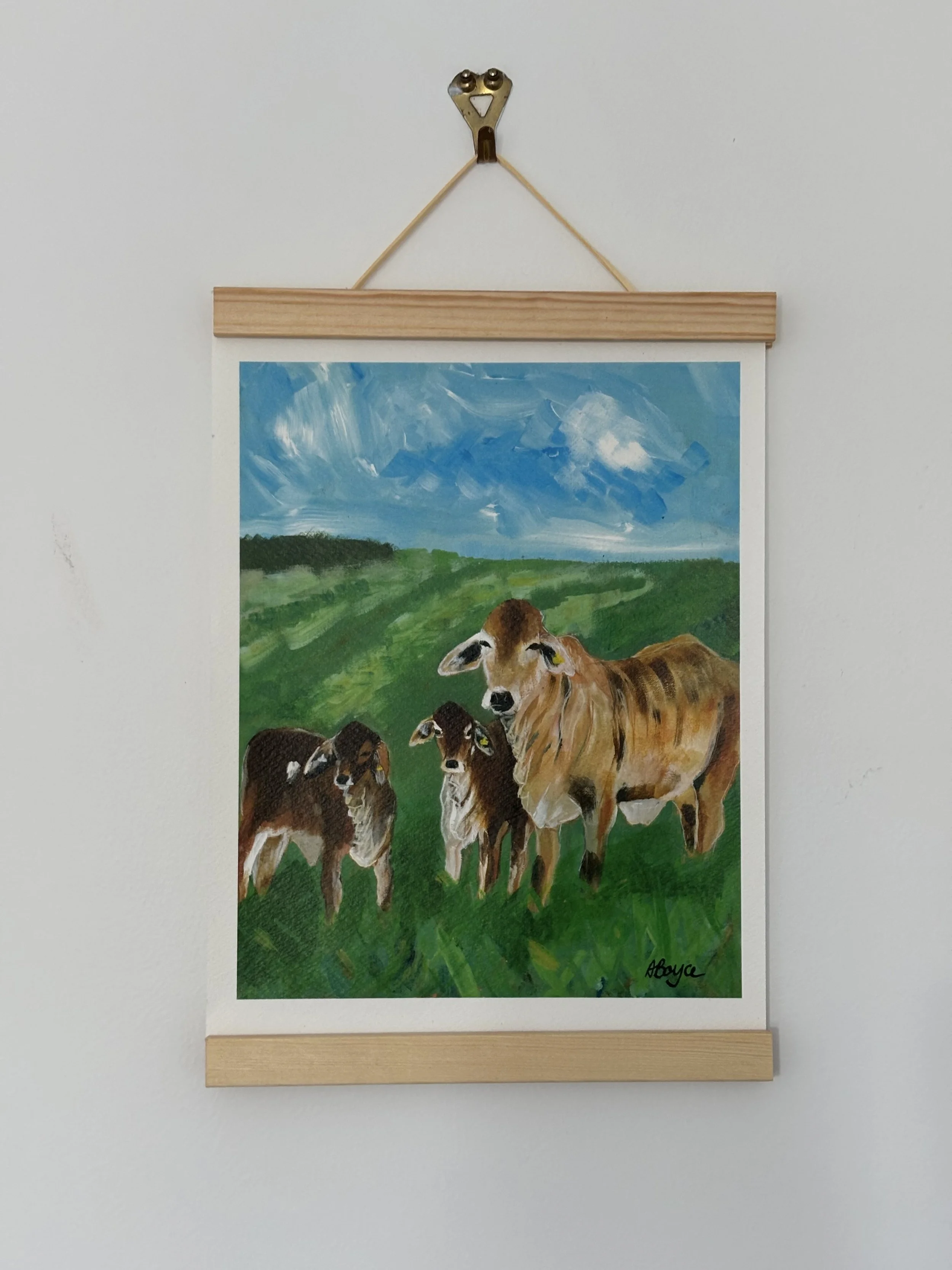 Painting of three cows on green pastures under a blue sky with clouds.